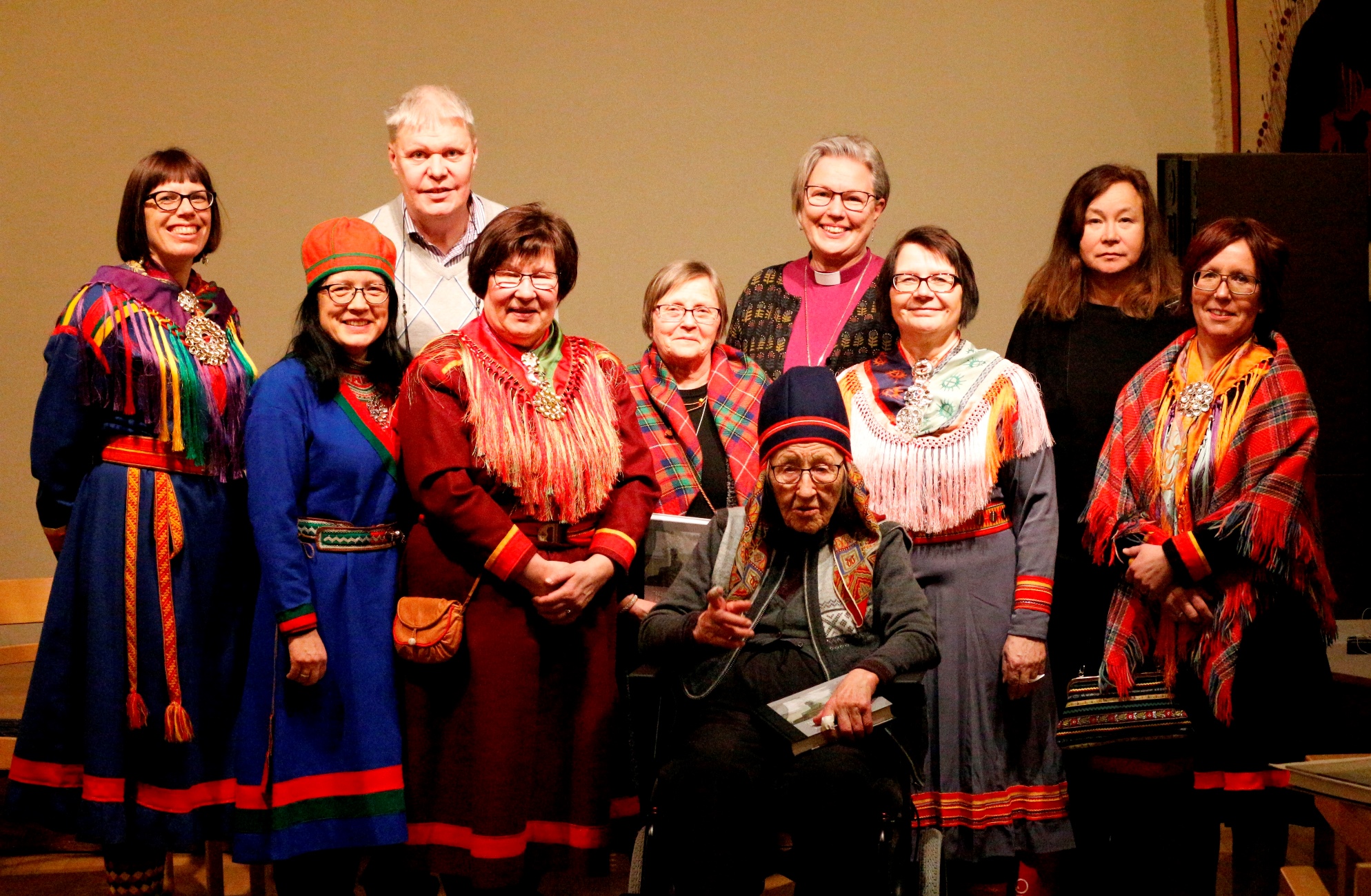 På plats när boken om nomadskolorna presenterades på Jokkmokks marknad: från vänster Kaisa Huuva, redaktör för boken, Sylvia Sparrock, Samiska rådet i Svenska kyrkan, Erik Oscar Oscarsson, medverkande i boken, Ingrid Inga, Samiska rådet i Svenska kyrkan, Sagka Stångberg, medverkande i boken, biskop Eva Nordung Byström, Härnösands stift, Ellacarin Blind redaktör för boken och Ylva Jannok Nutti, medverkande i boken. Längst fram sitter Ibb Ristin Tuorda, 99 år och den äldsta medverkande i boken.