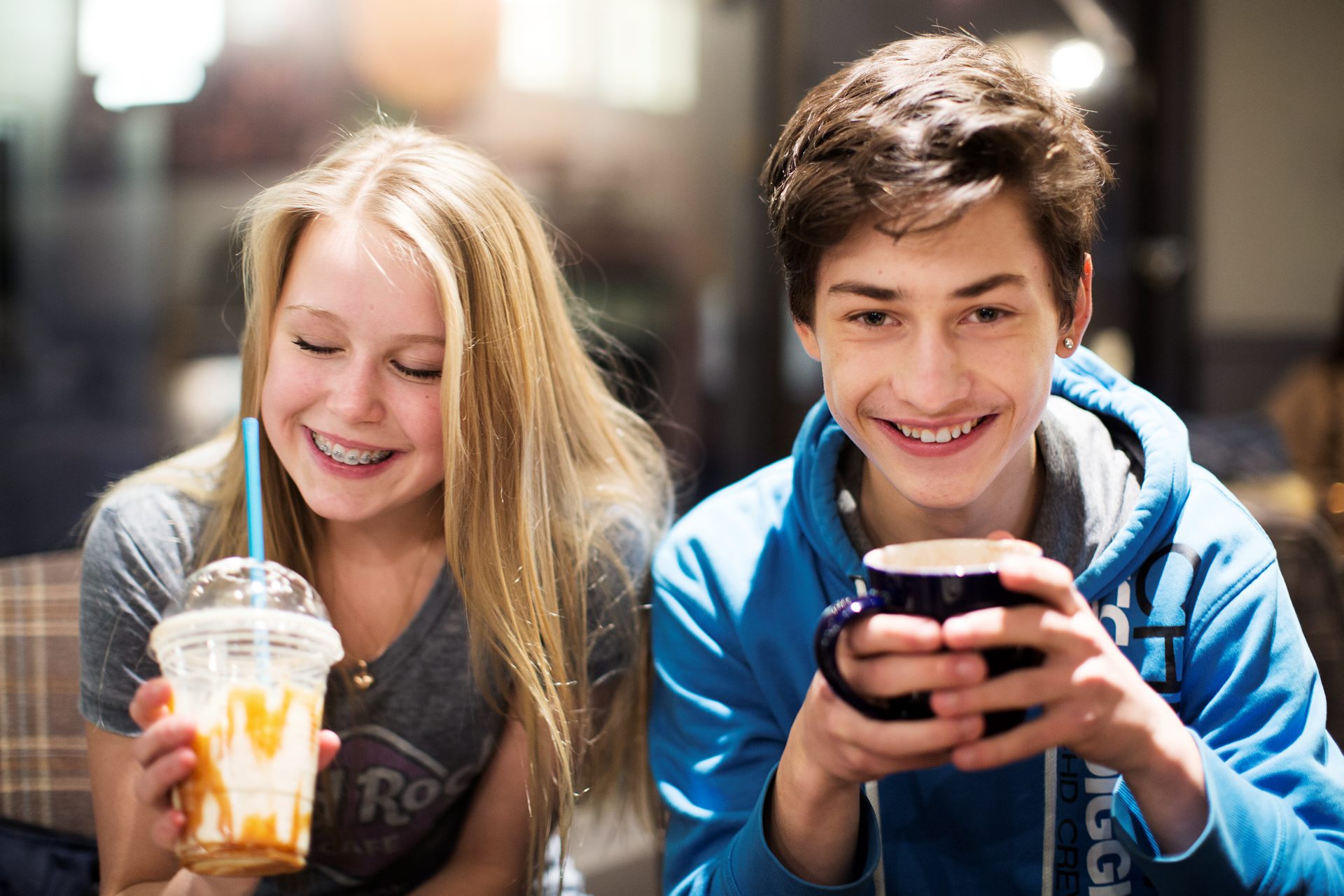 Två leende ungdomar sitter och fikar.