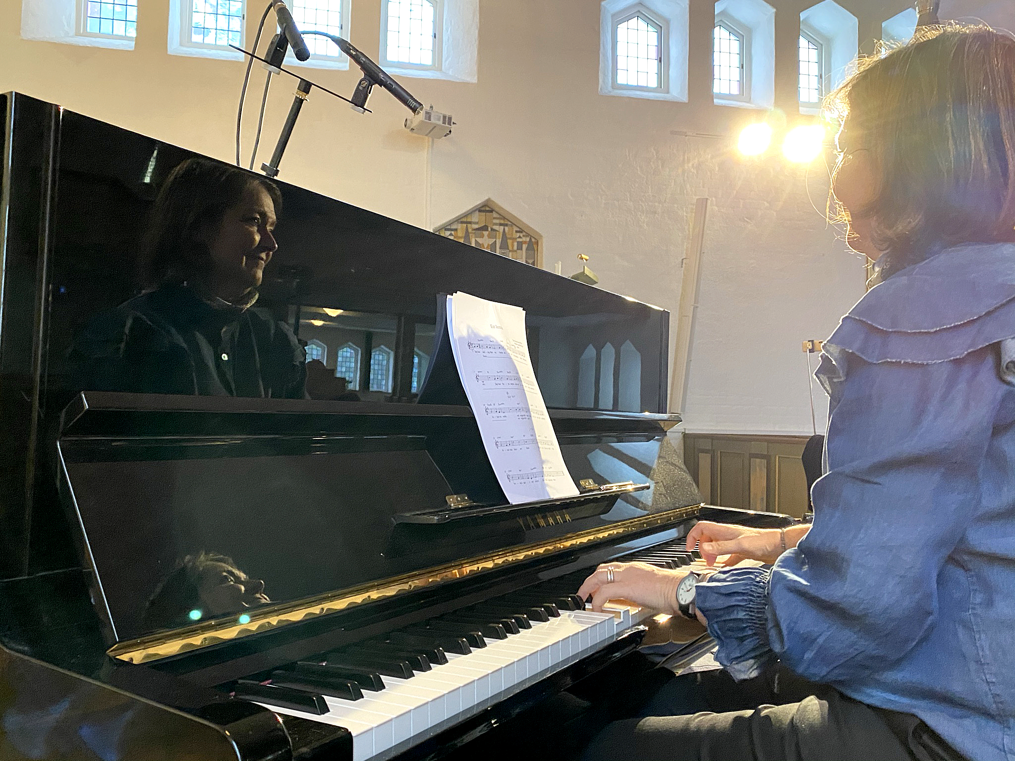 Musiker spelar piano och reflekteras i instumentet