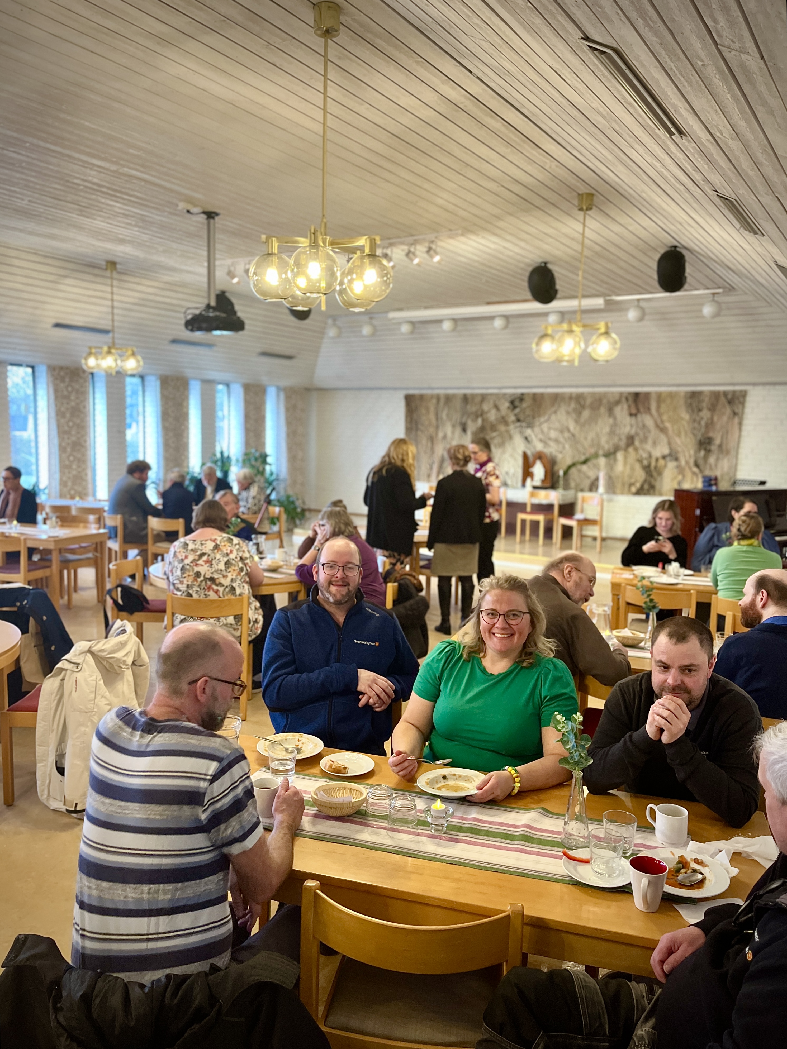 Ett gäng människor sitter i en församlingssal och äter soppmiddag.