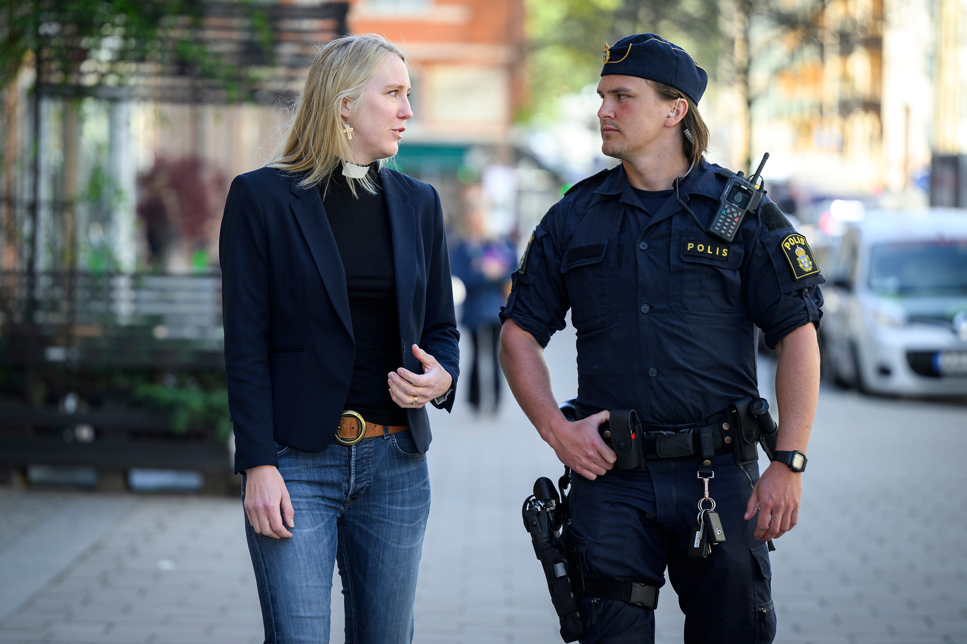 En präst och en polis går på en gata och pratar med varandra.