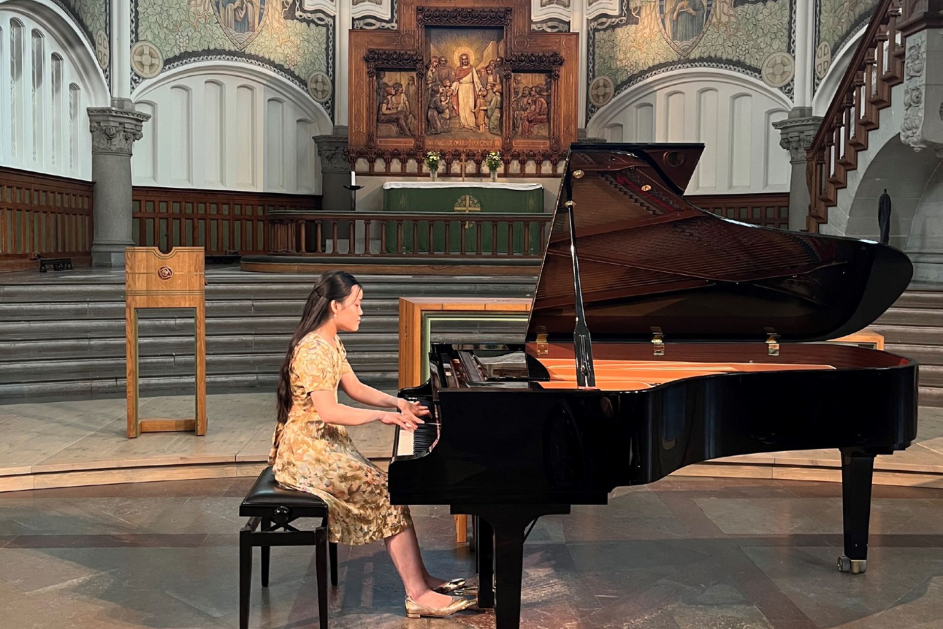 Bild på en pianist som spelar på en flygel i en kyrka.