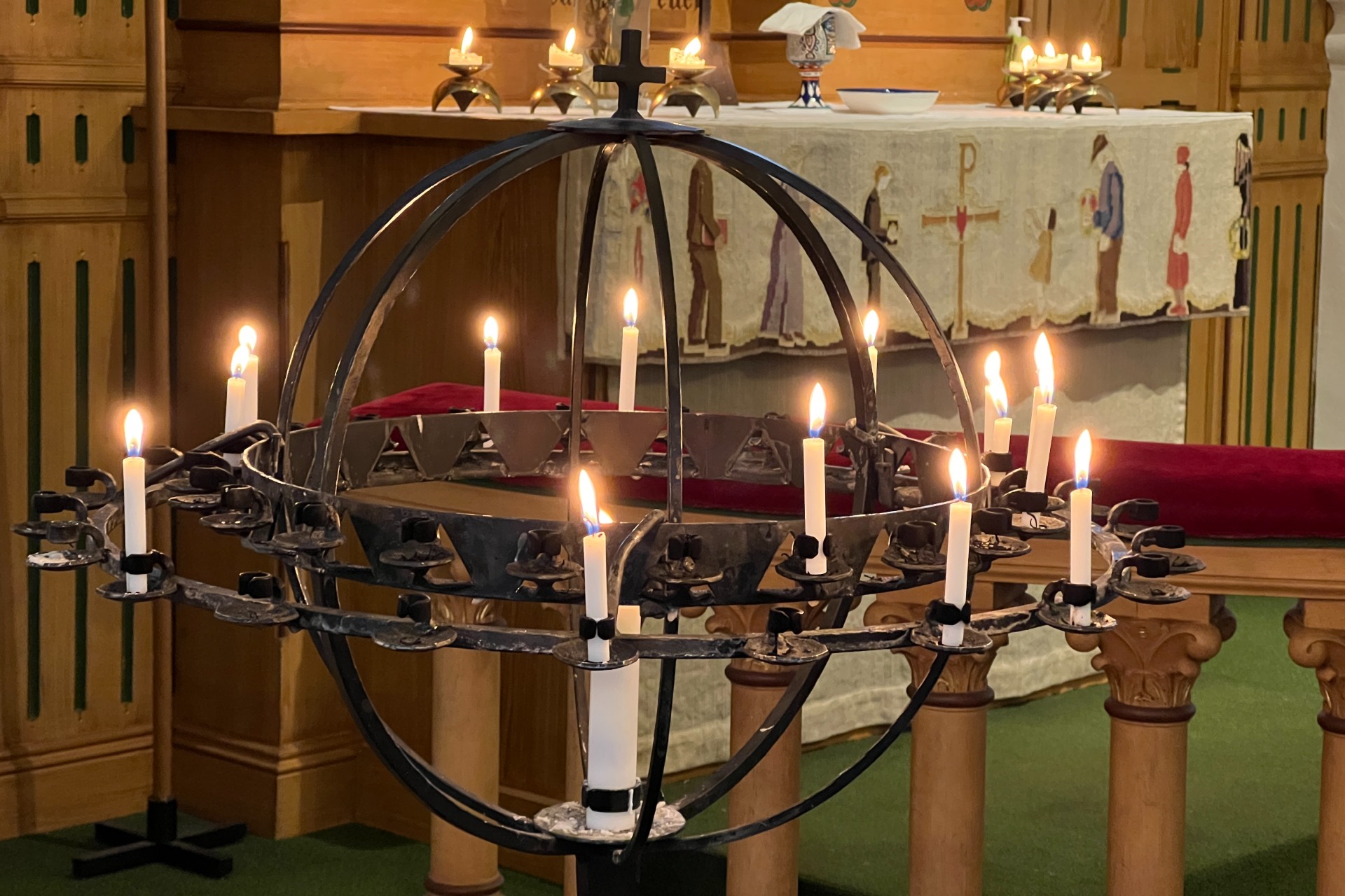 En svart smides ljusbärare med tända böneljus.