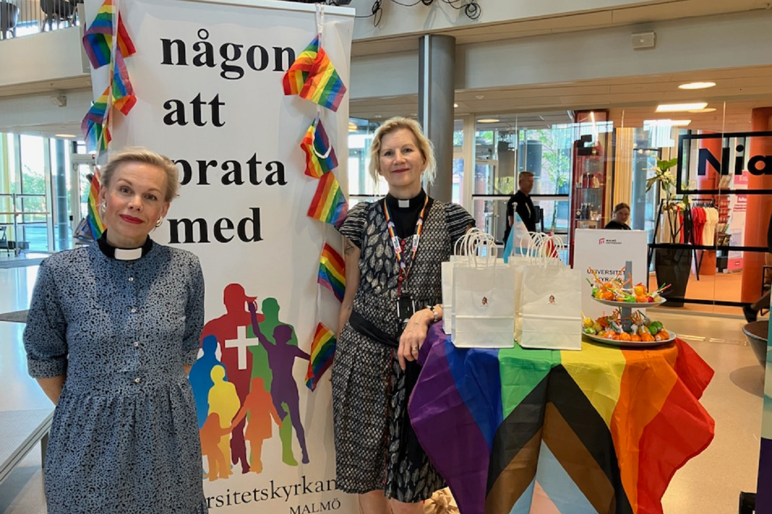 Två kvinnor står framför en rollupskylt.