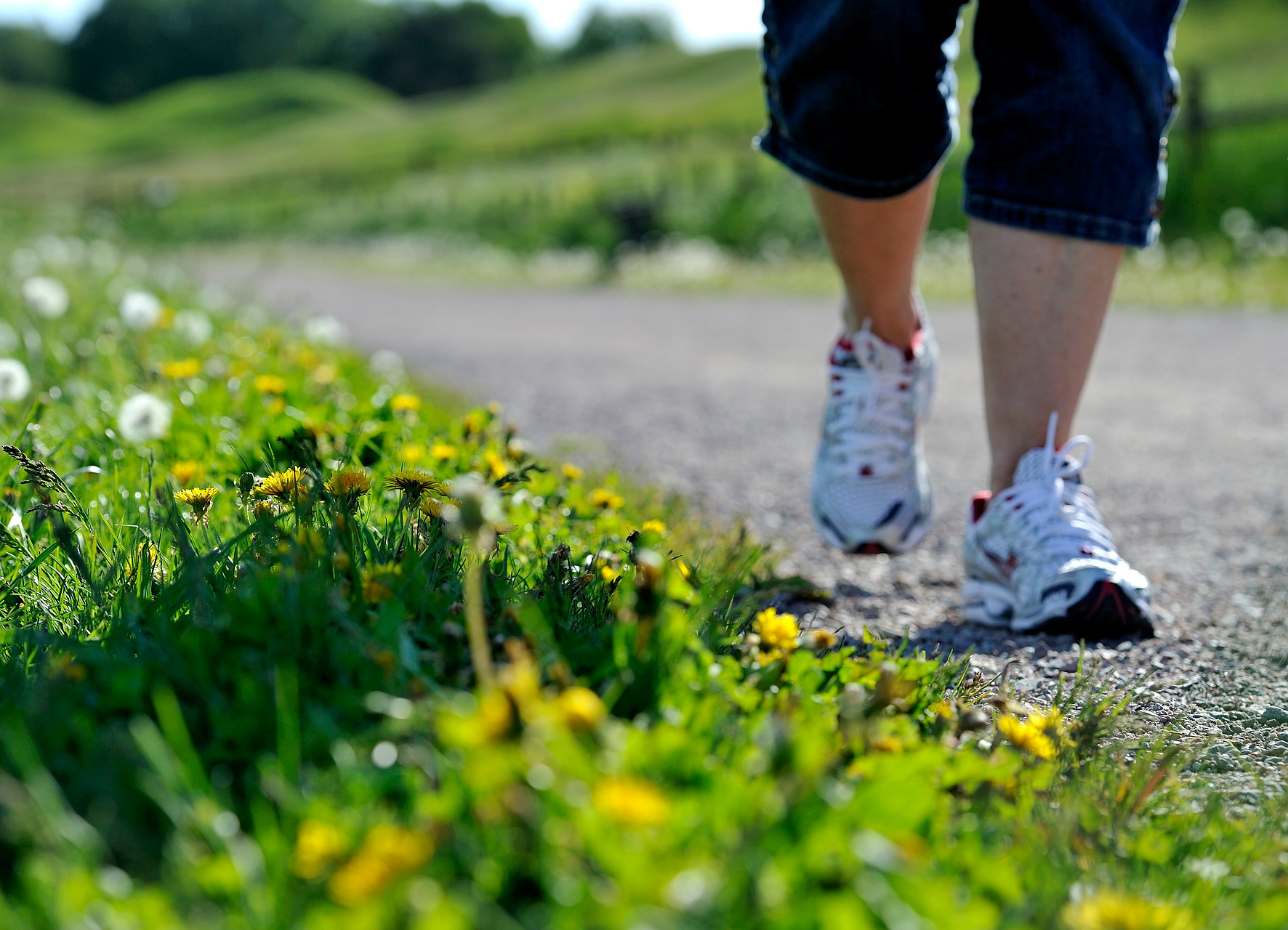 Fötter som går på grusväg vid grönt gräs.