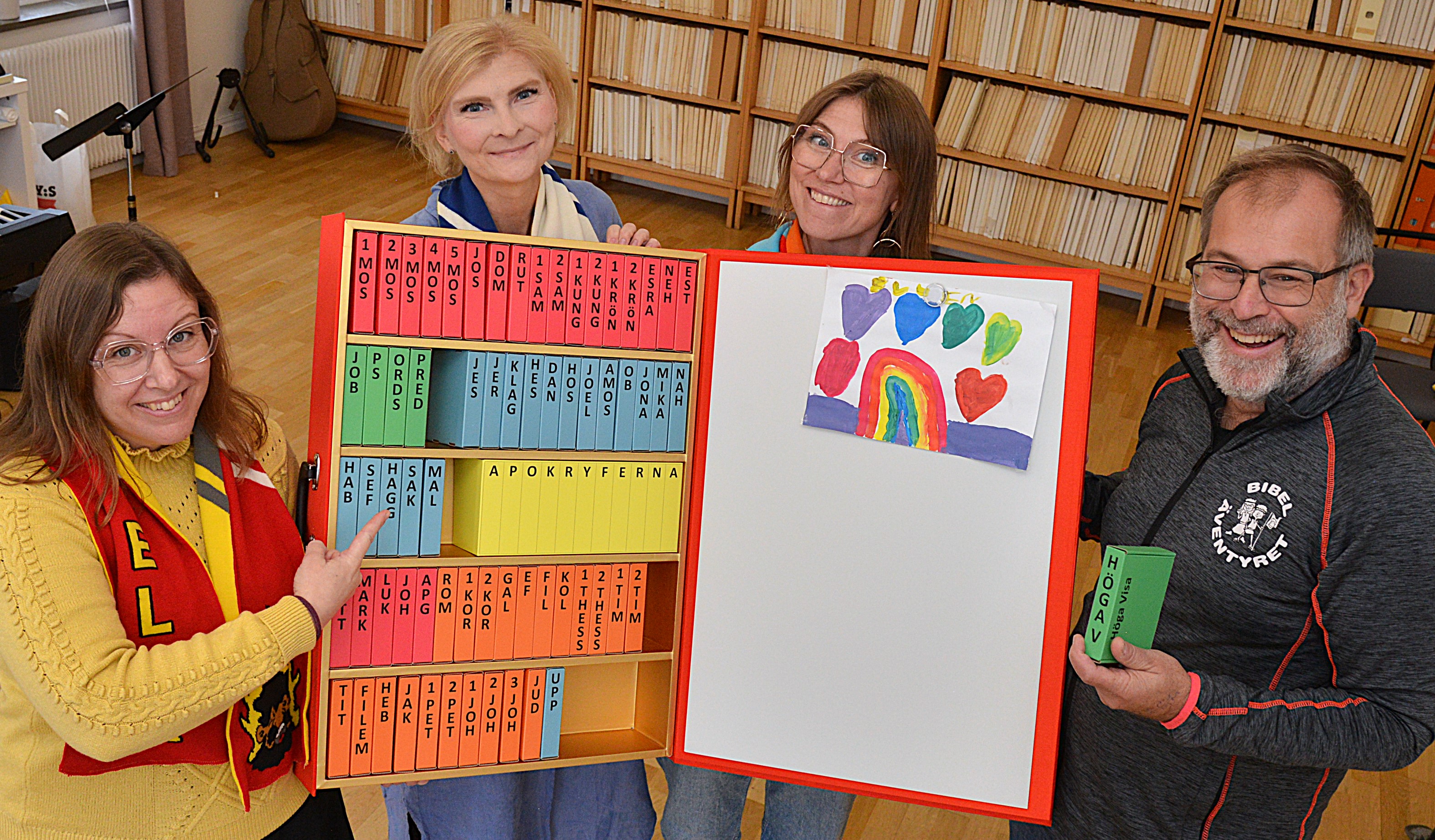 Tre kvinnor och en man står och håller i en stor Bibel.