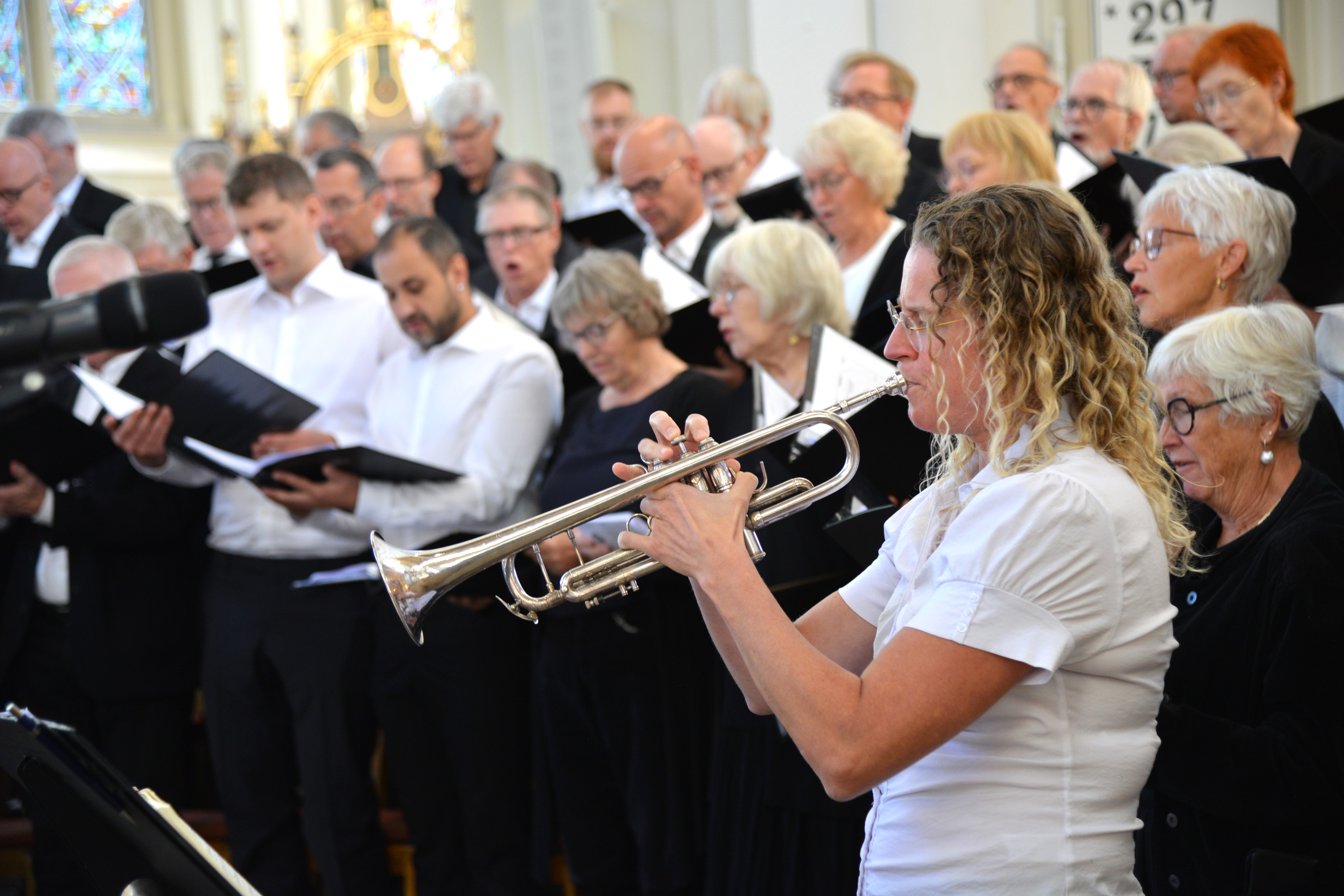 Sångkör i bakgrunden och en kvinna på kornett i förgrunden
