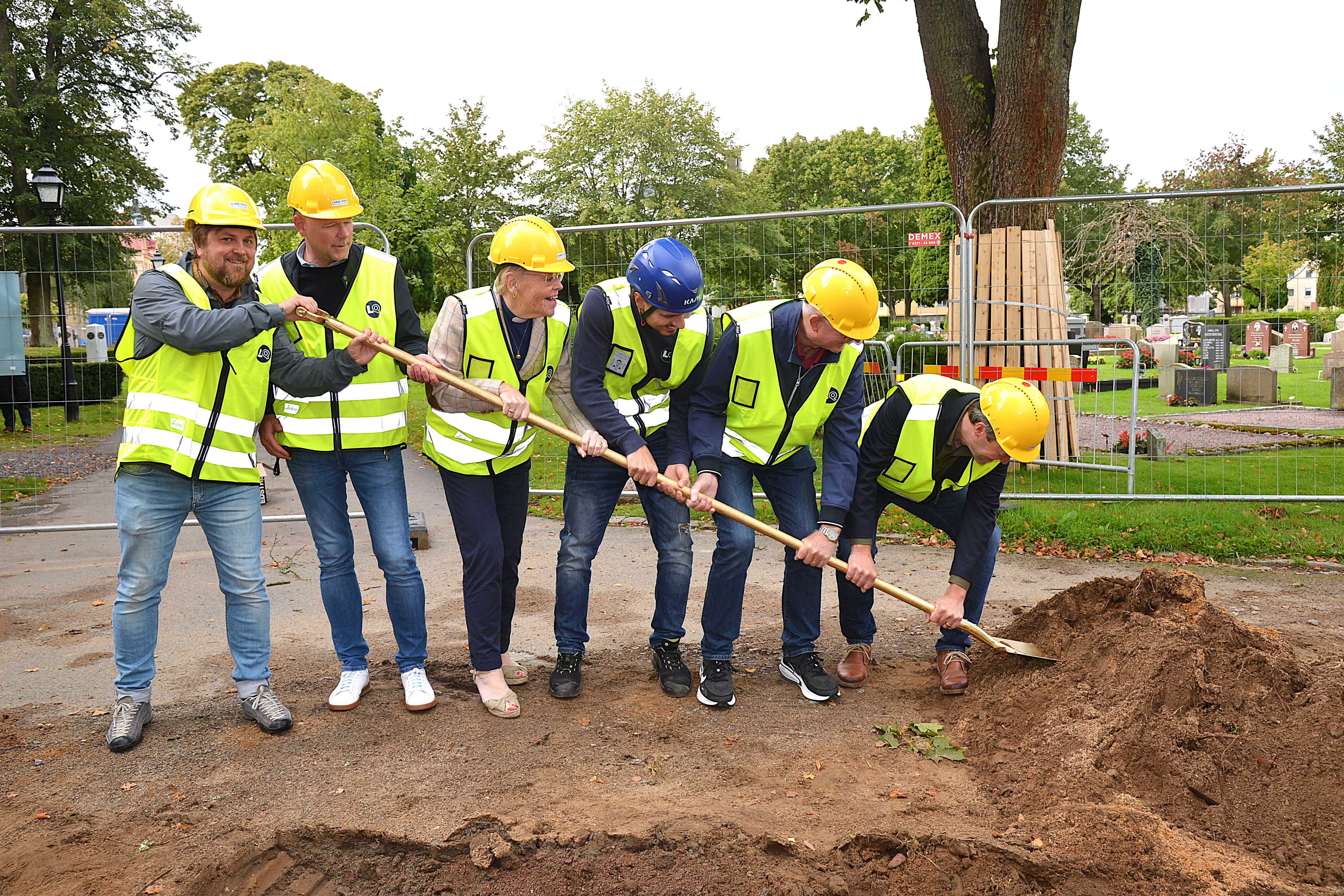 Ett antal personer står och gräver med en gemensam spade