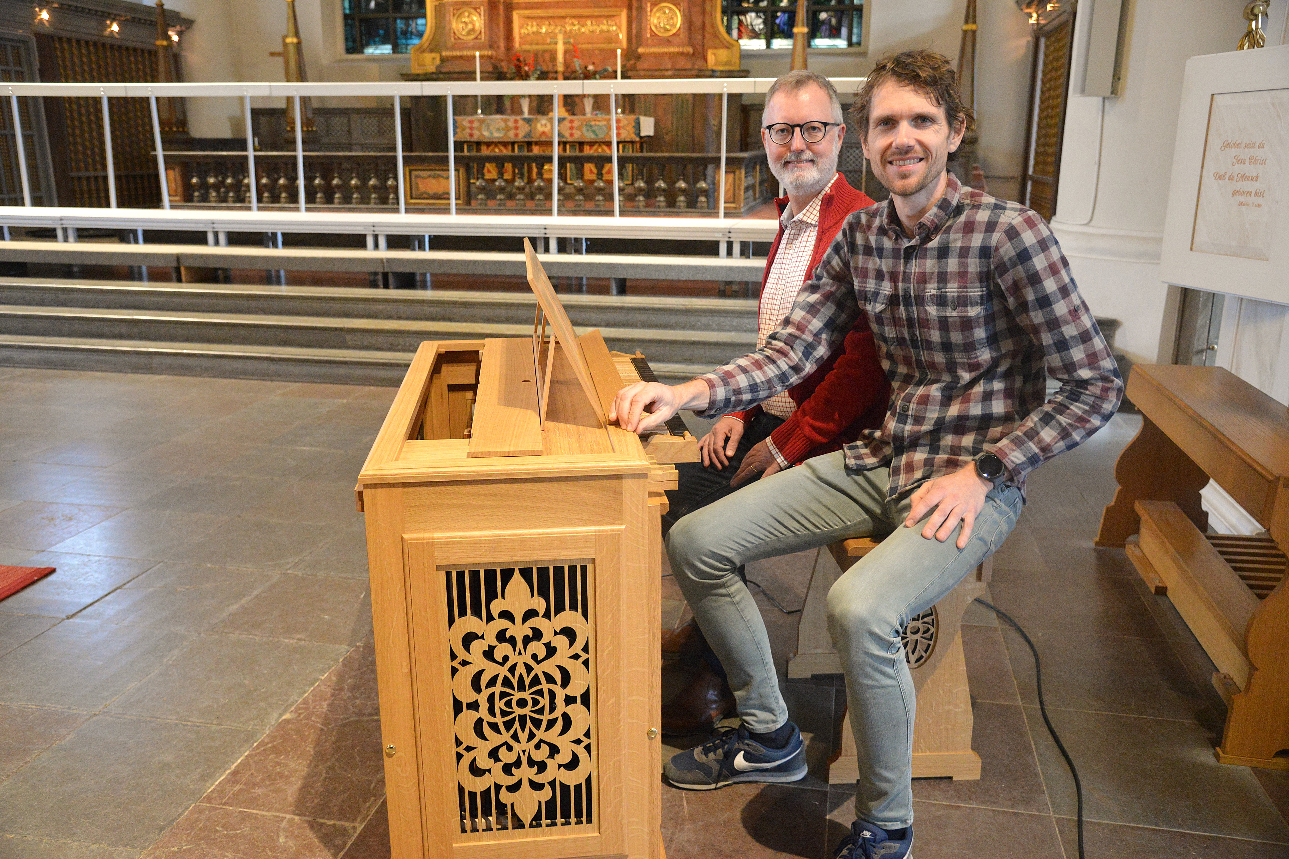 Två män sitter vid en liten orgel