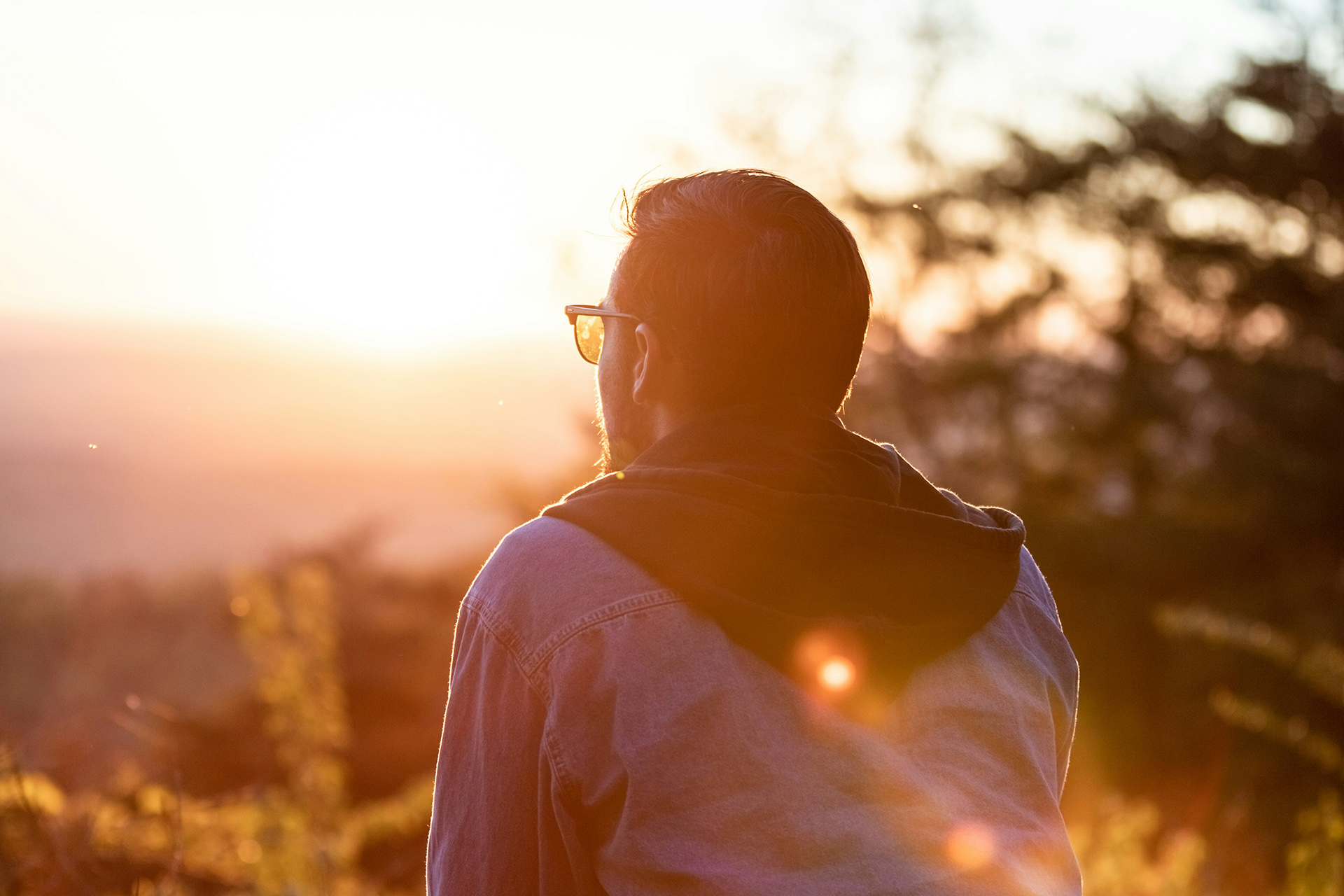 En person sitter och tittar ut över en solnedgång.
