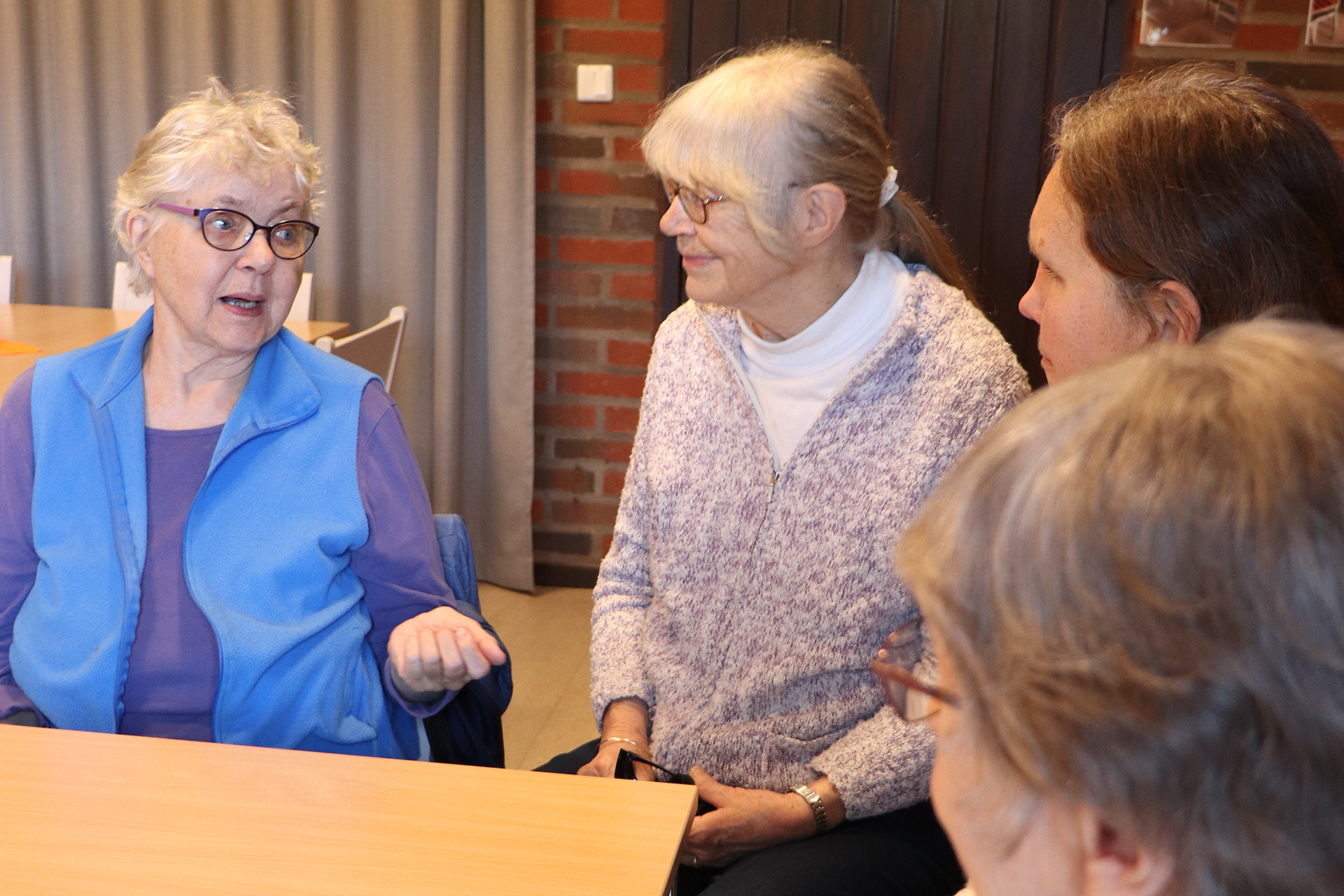 Fyra kvinnor samtalar vid ett bord. 