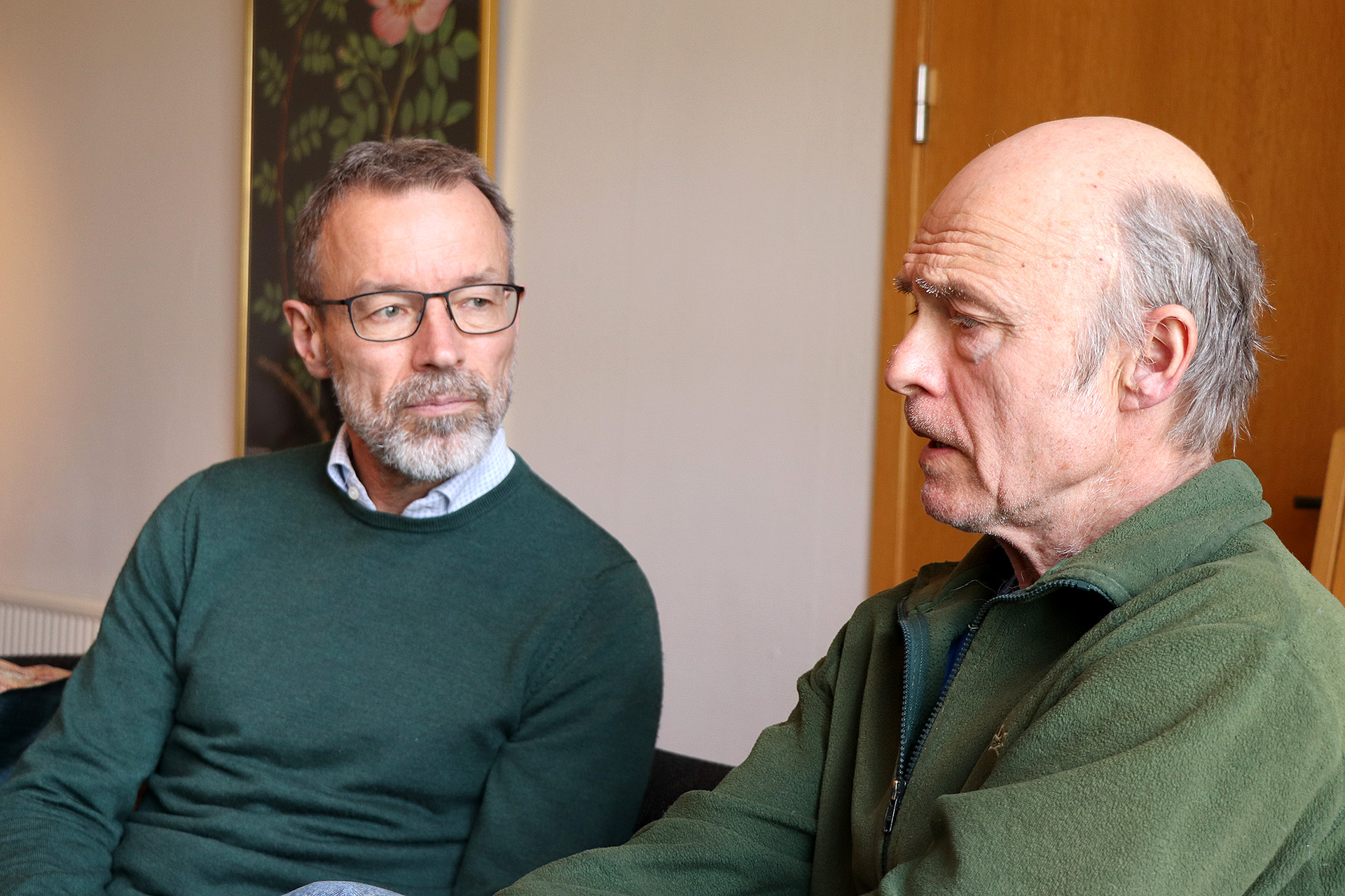 Två män sitter och pratar med varandra. 