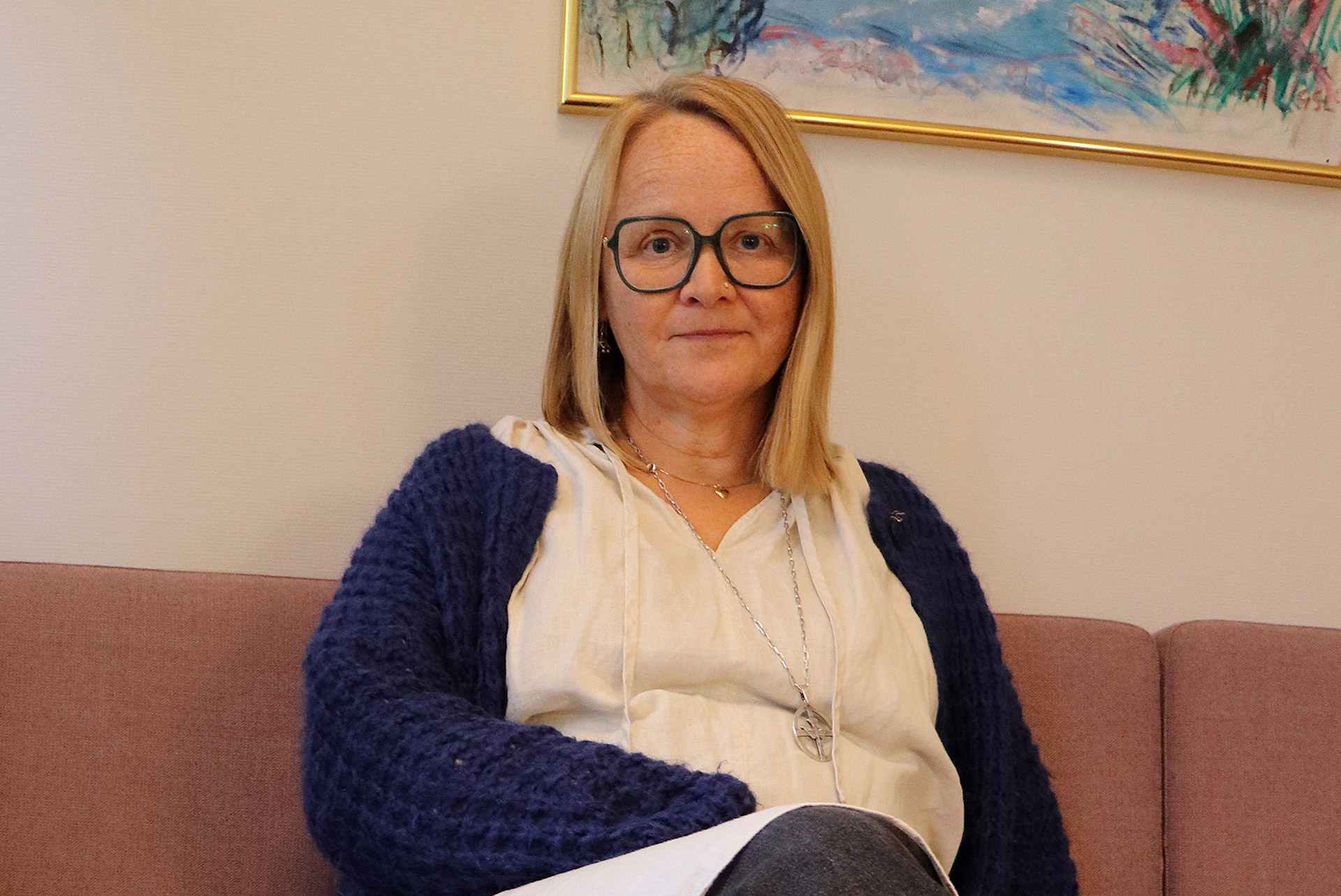 En kvinna med diakonsmycke sitter i en soffa. 