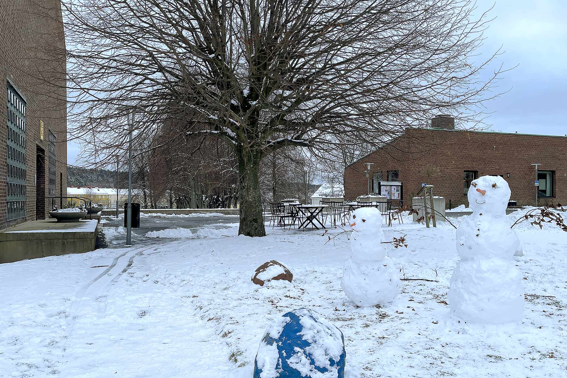 Två snögubbar framför kyrkobyggnader.