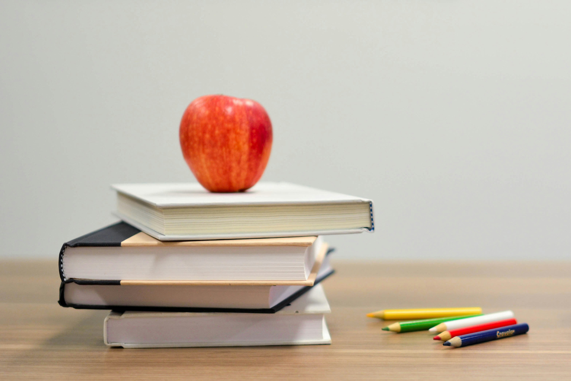 Ett äpple ligger på en hög med böcker.