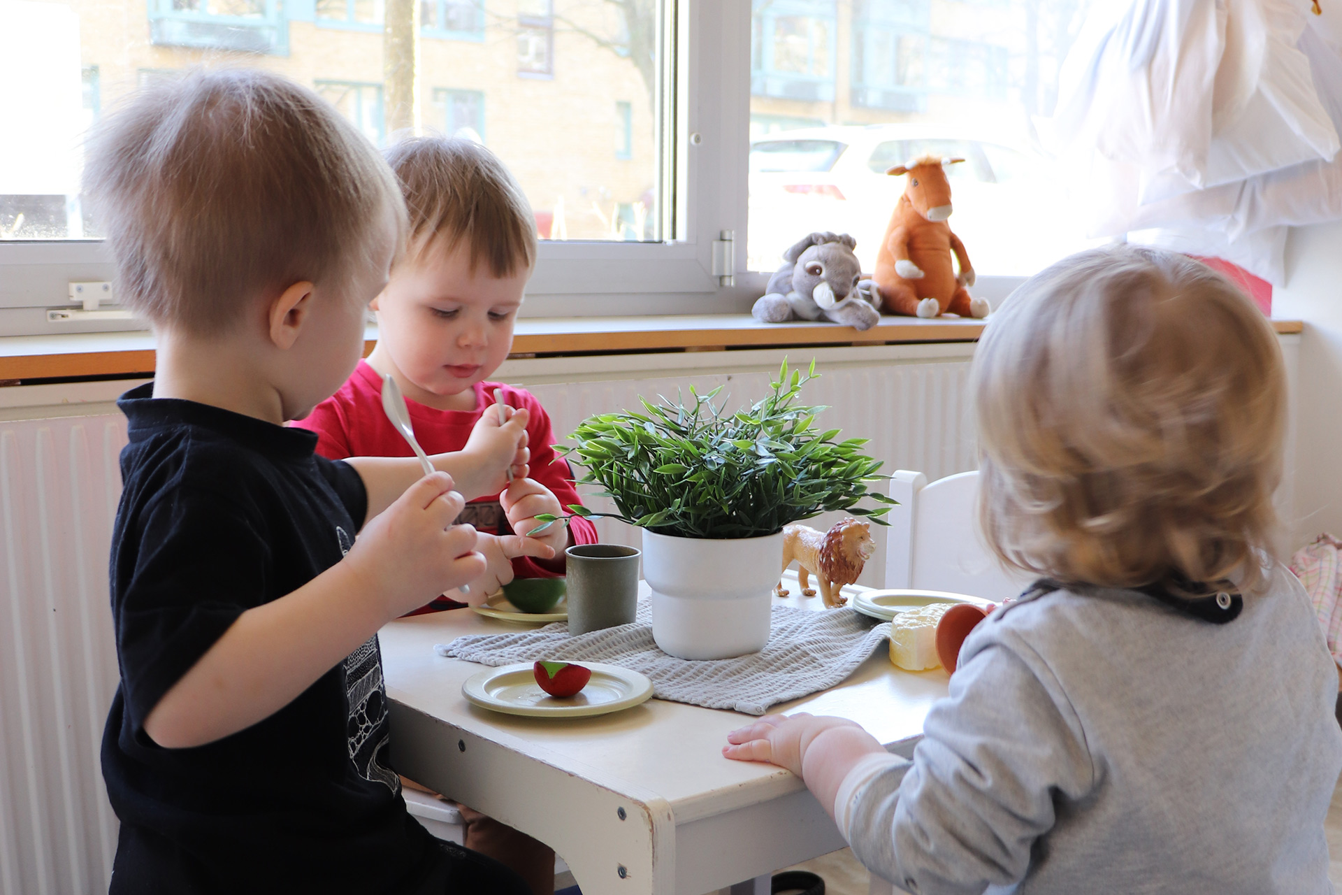 Tre barn leker vid ett bord.