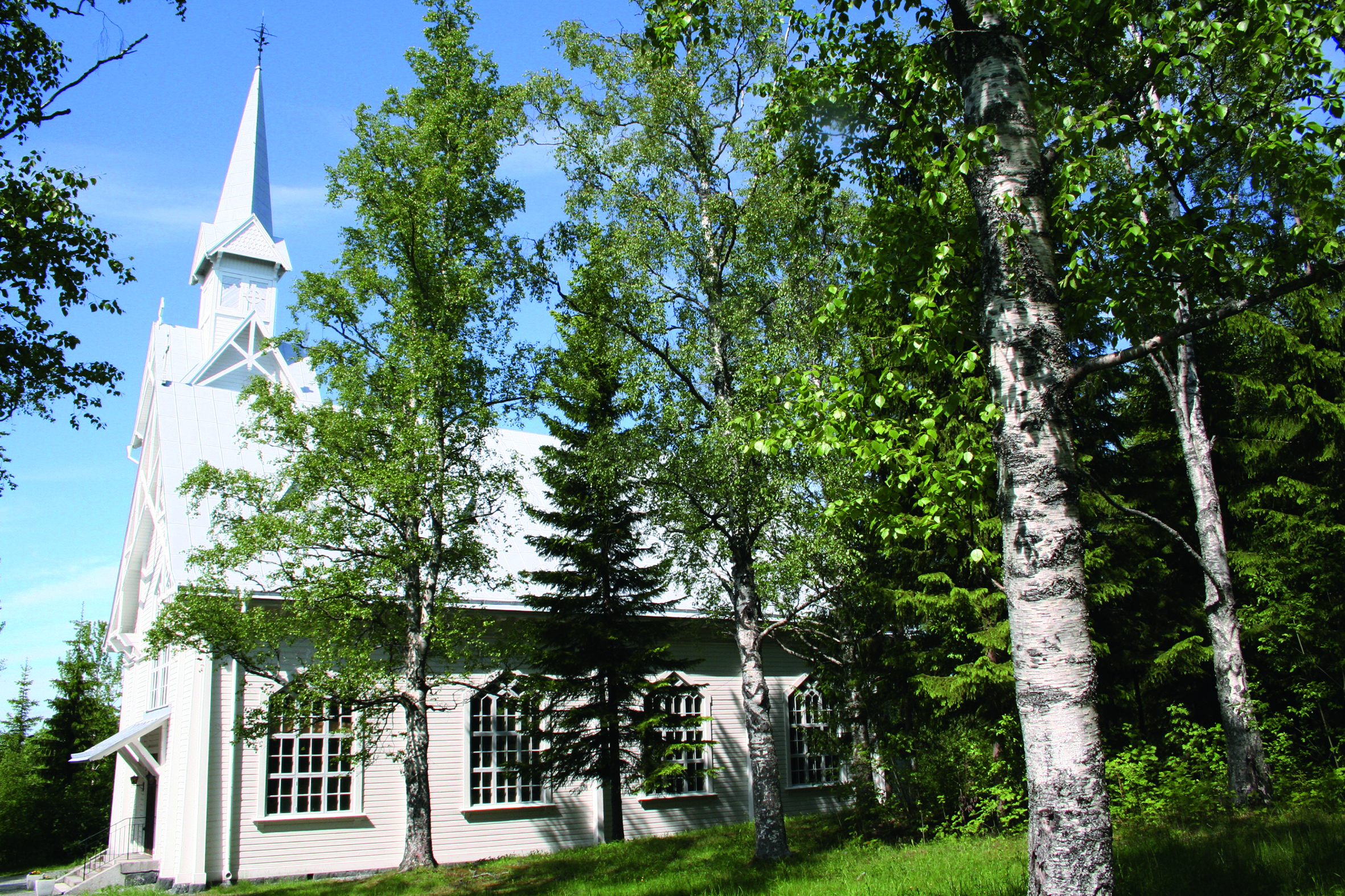 Kramfors kapell skymtar bakom några björkar