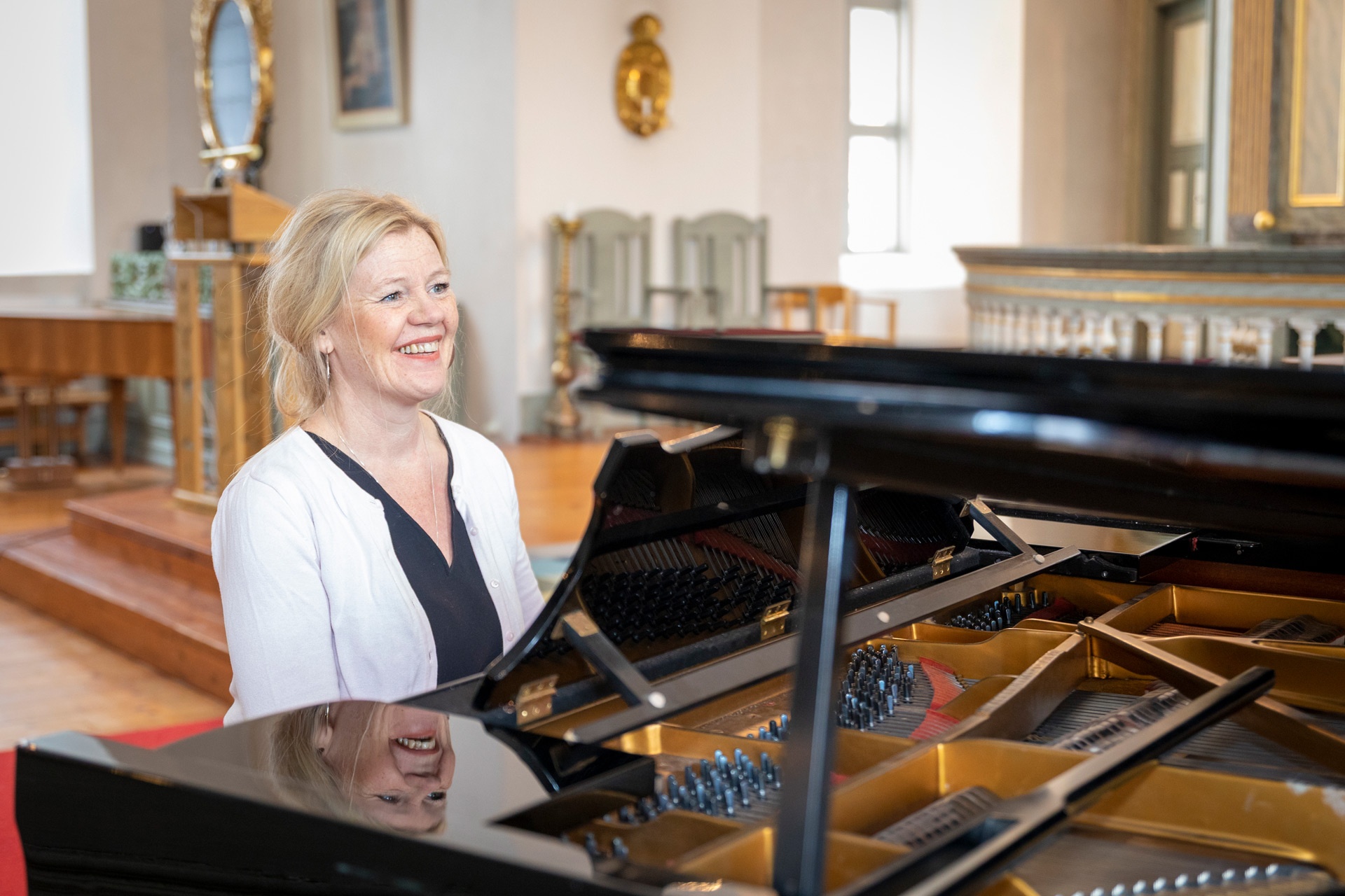 En kvinnlig kantor sitter vid en flygel.