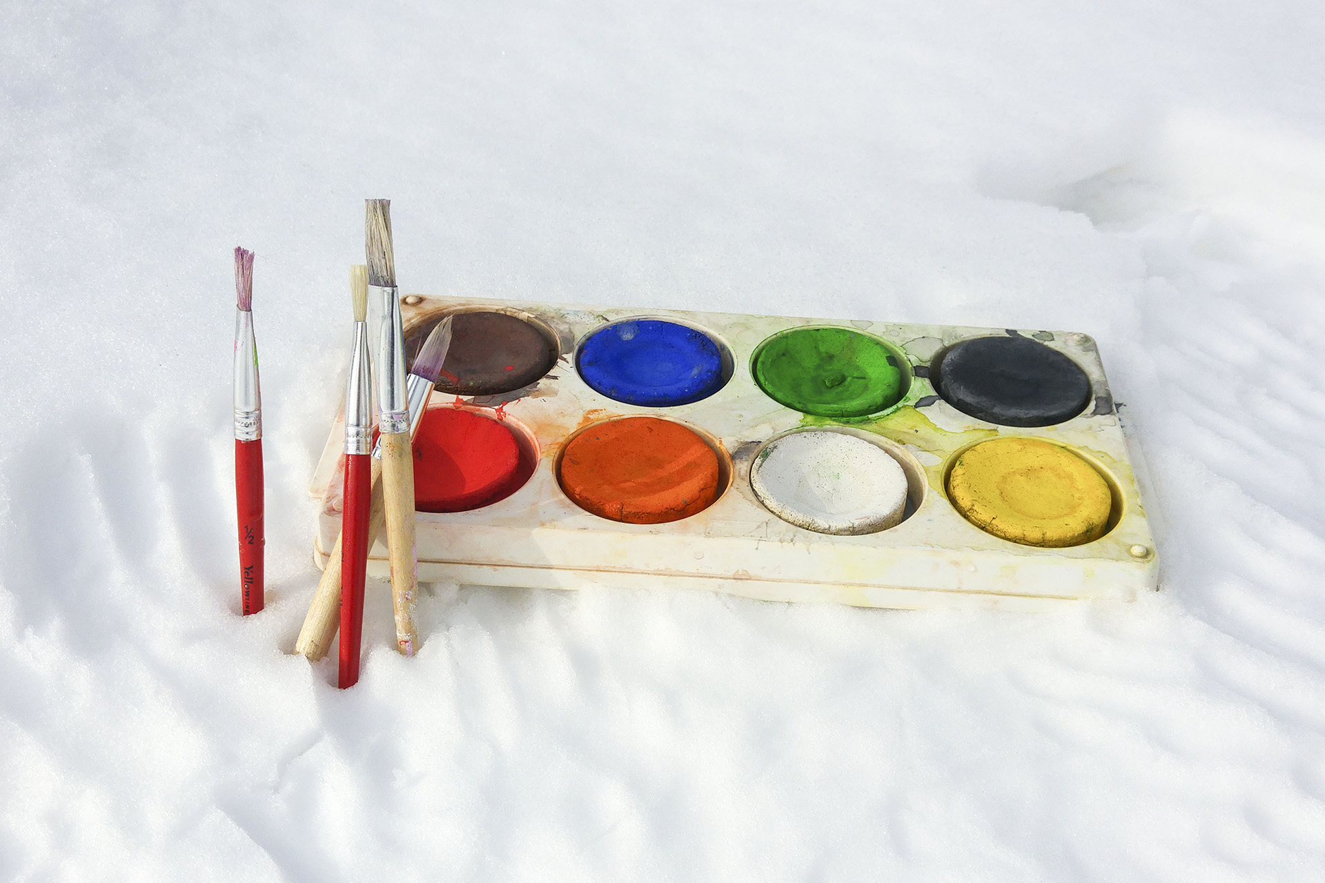 Penslar och vattenfärgspalett stående i snö.