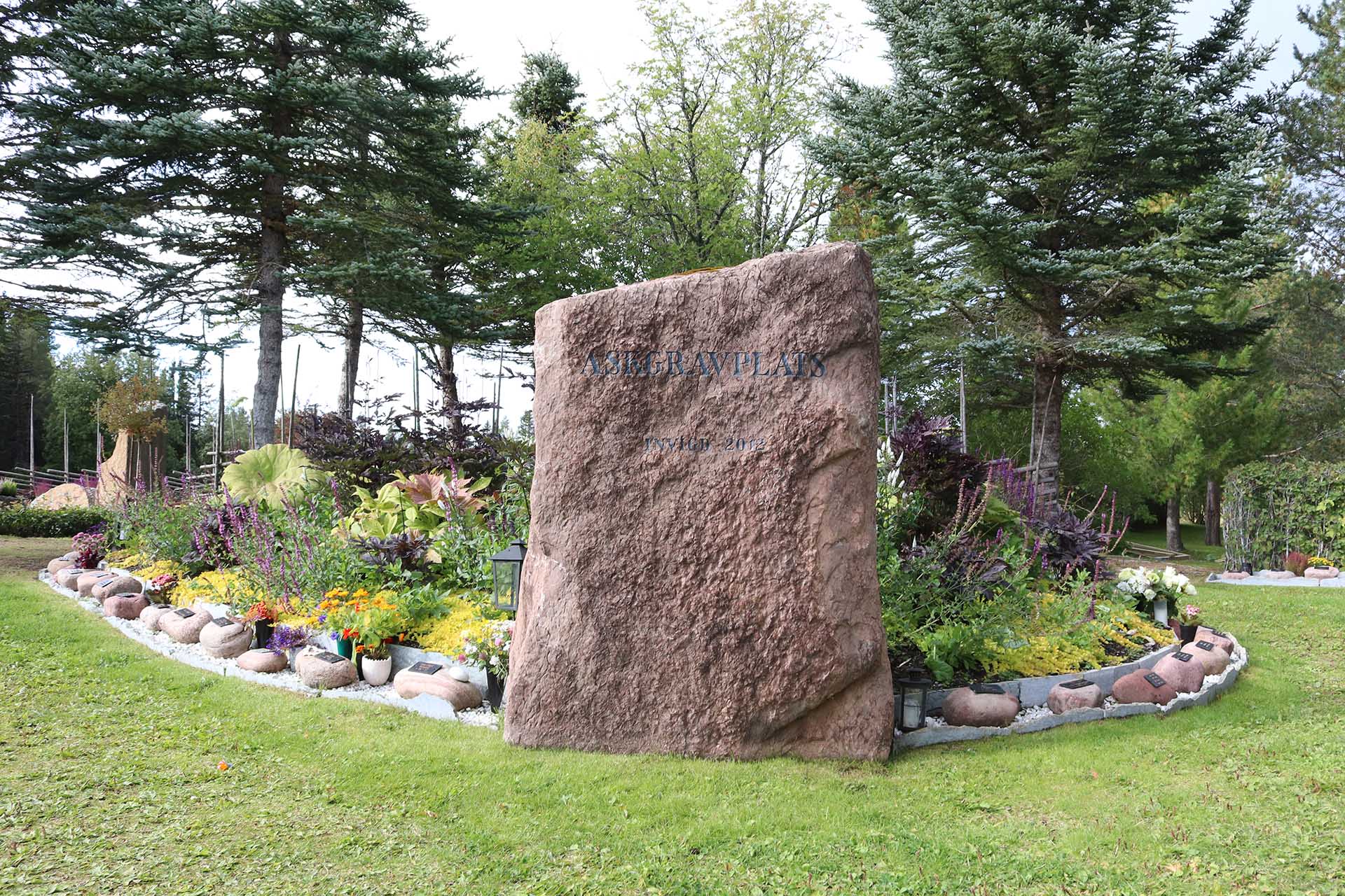 Gravområde på kyrkogård med stor sten märkt ASKGRAVPLATS