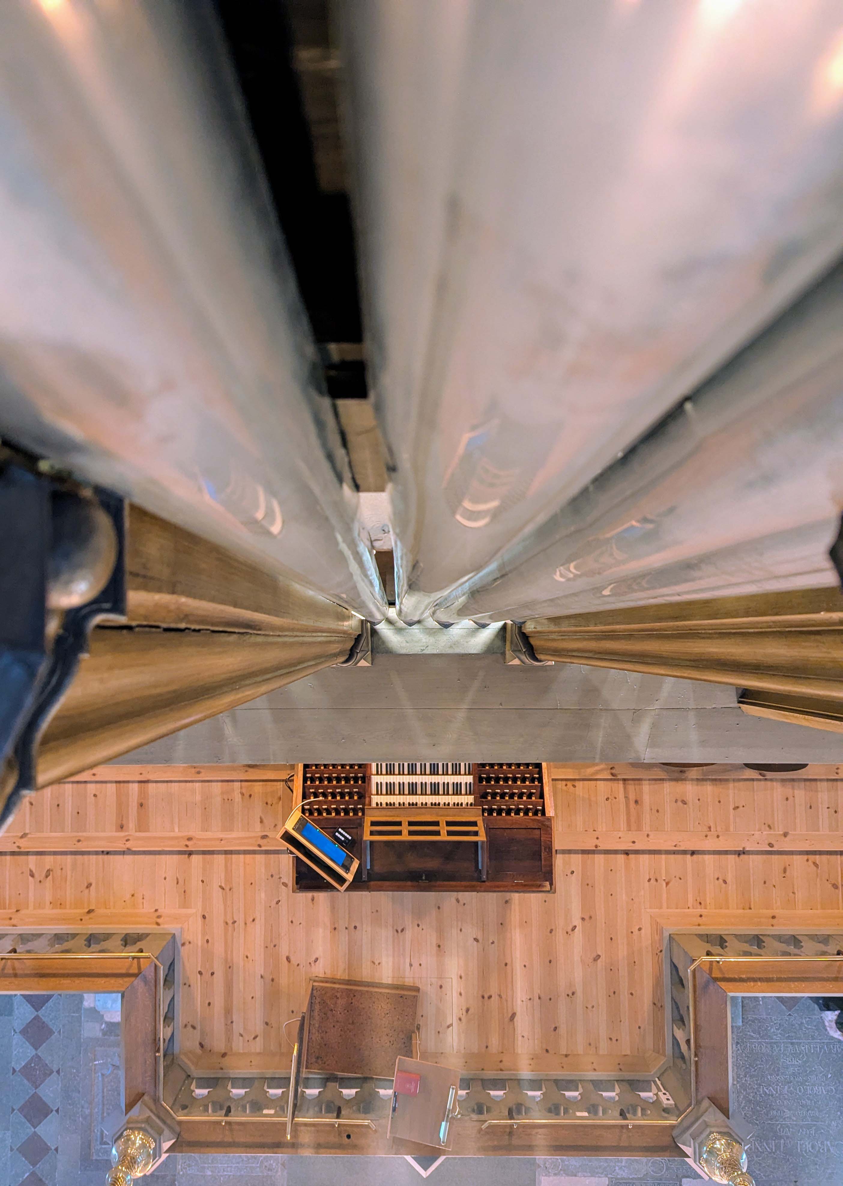 Åkermanorgelns spelbord sett rakt uppifrån längs med de nästan tio meter höga orgelpiporna i en lätt svindlande bild.