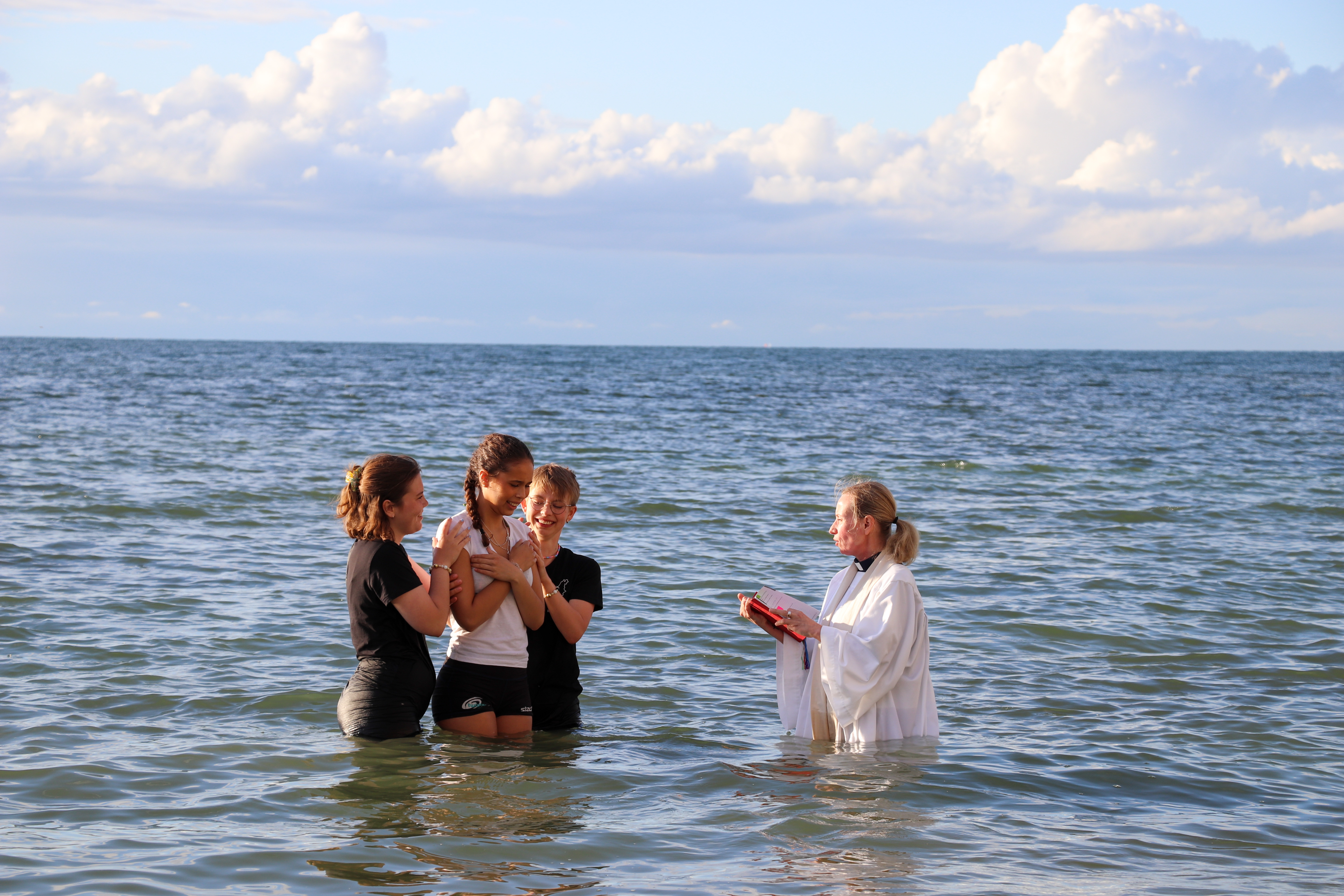 En konfirmand som döps i havet.