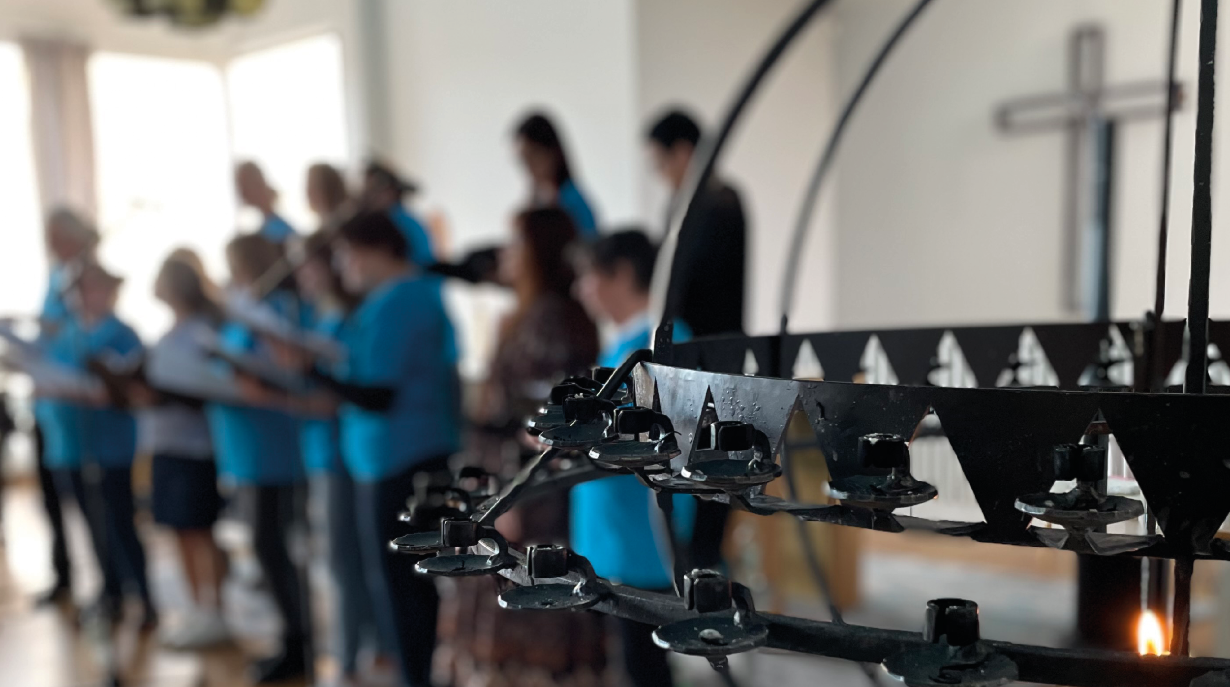 Suddig bild på Fisksätra Community Choir och en ljusbärare i förgrunden.