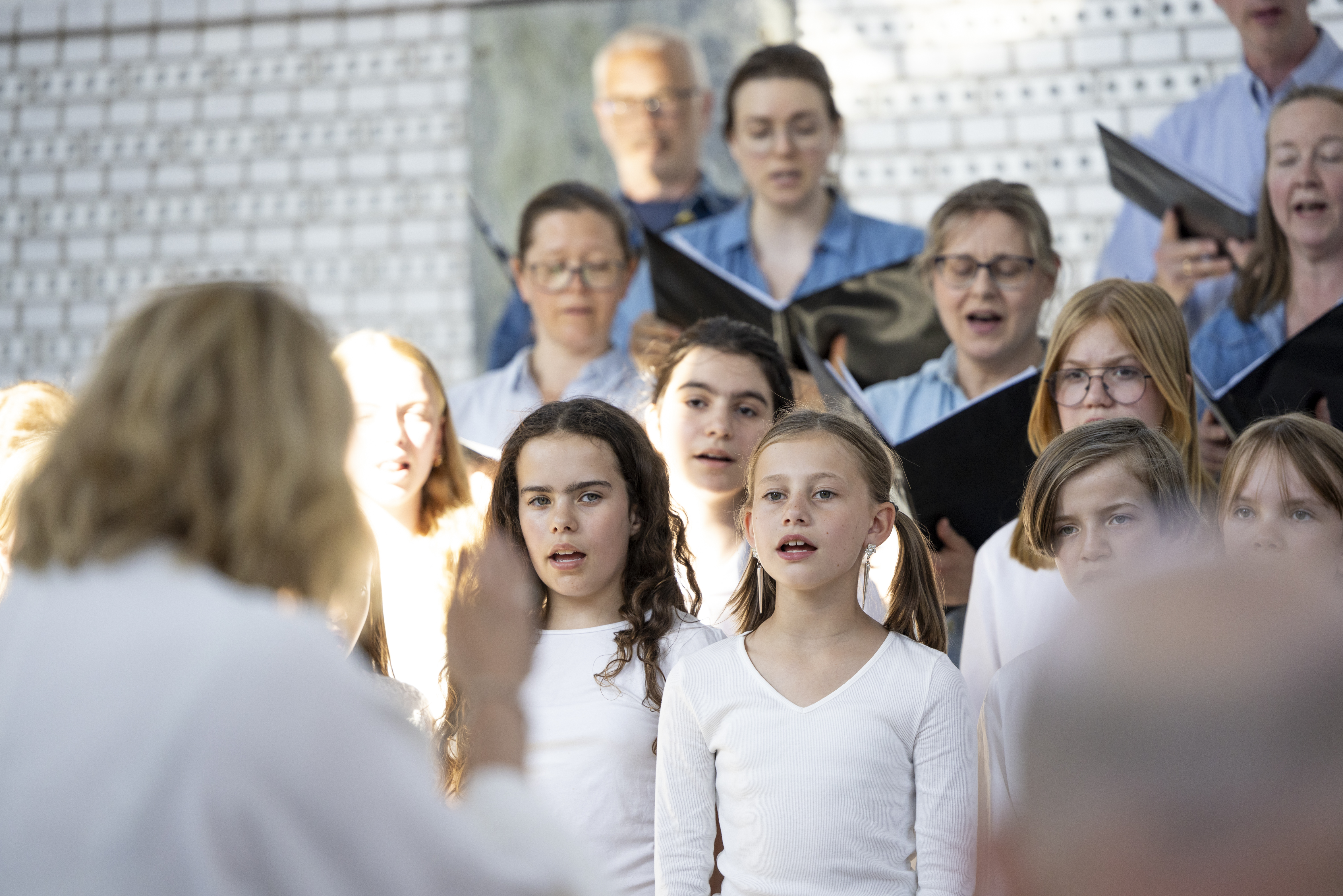 Körsångare i olika åldrar i Årsta kyrka, med körledaren i förgrunden