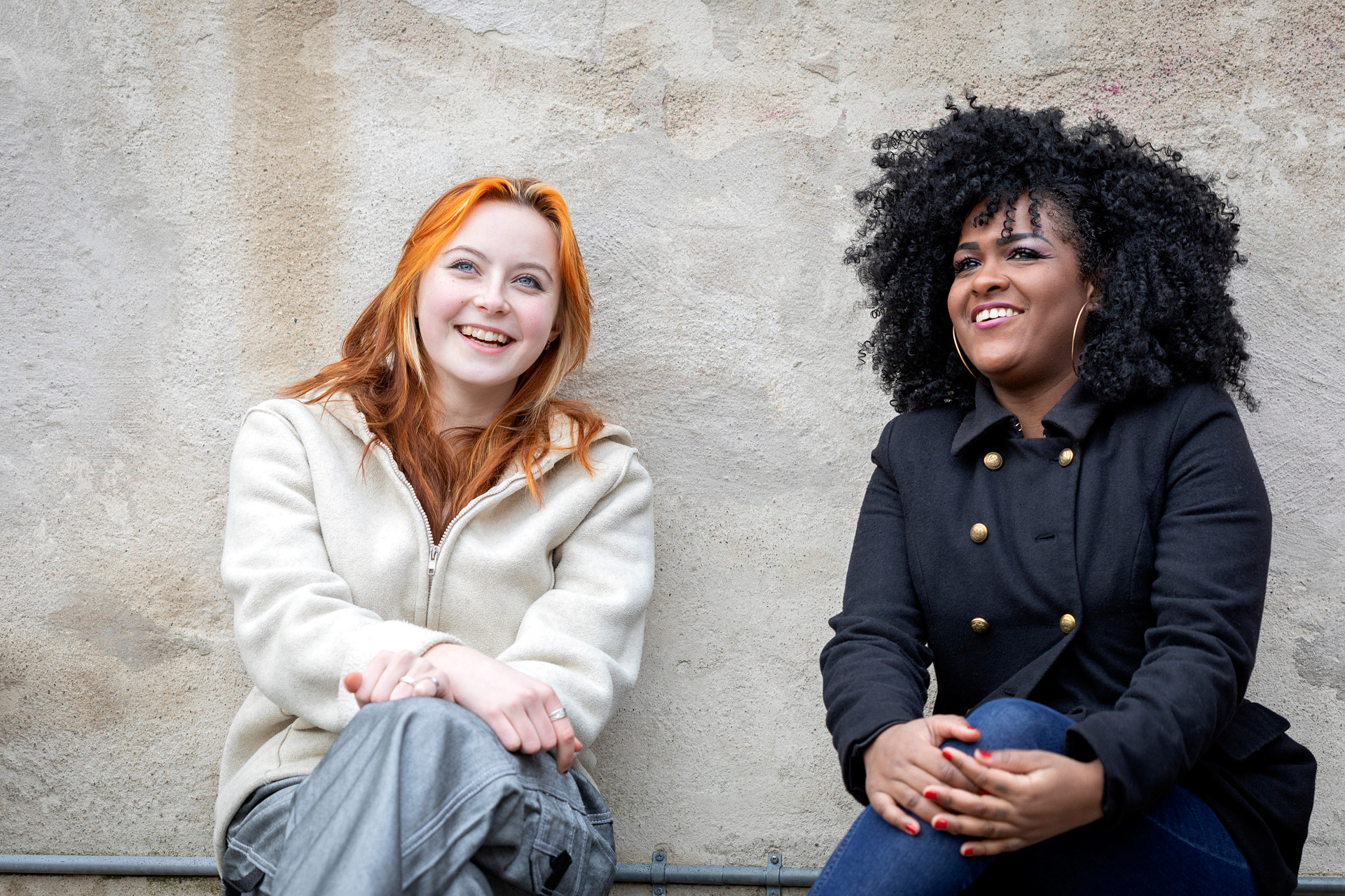 två unga kvinnor sitter på bänk