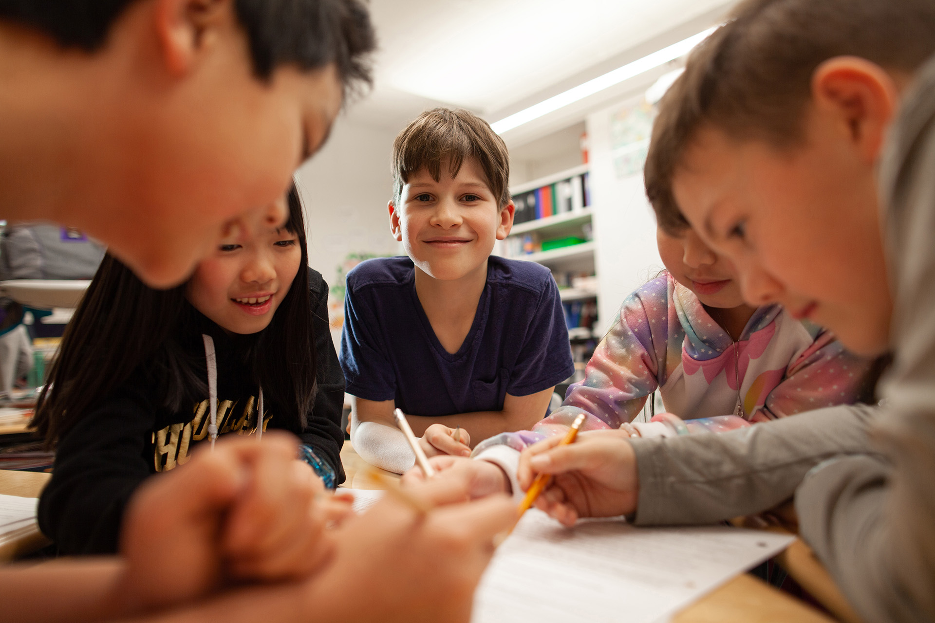 Fem barn pysslar vid bord