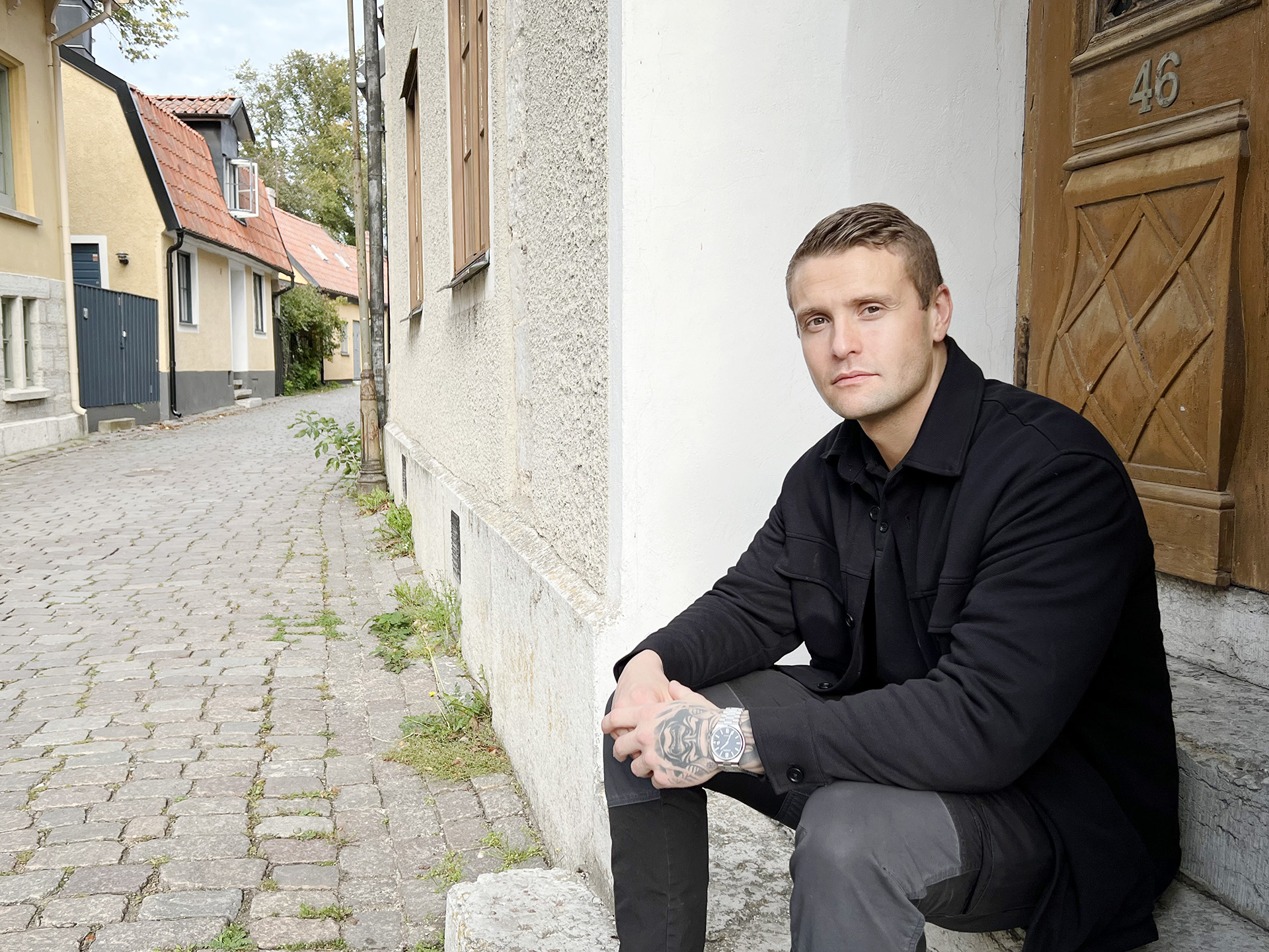 man sitter på trappa utanför ytterdörr i stad