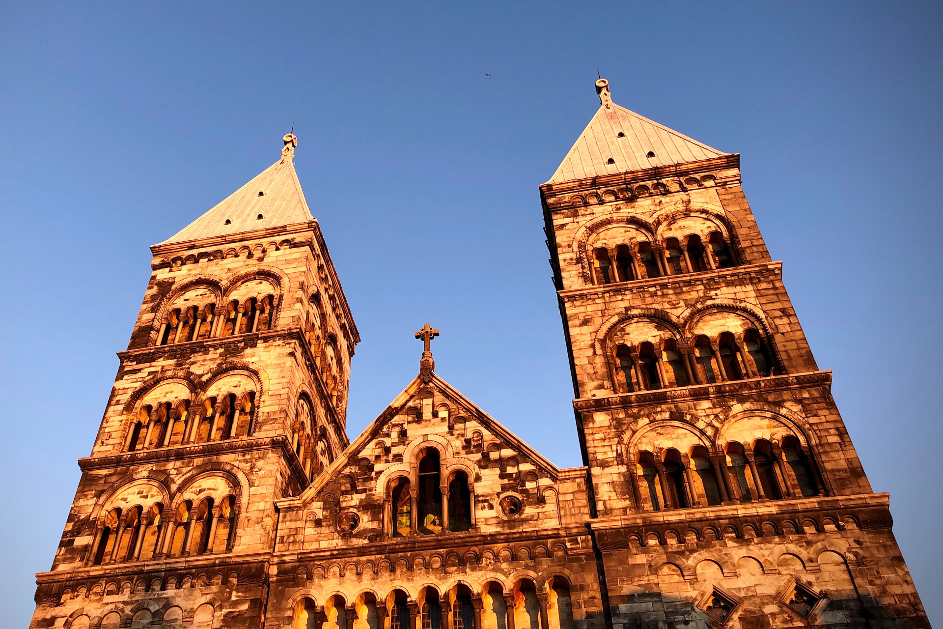 Lunds domkyrka i orange ljus med blå himmel.