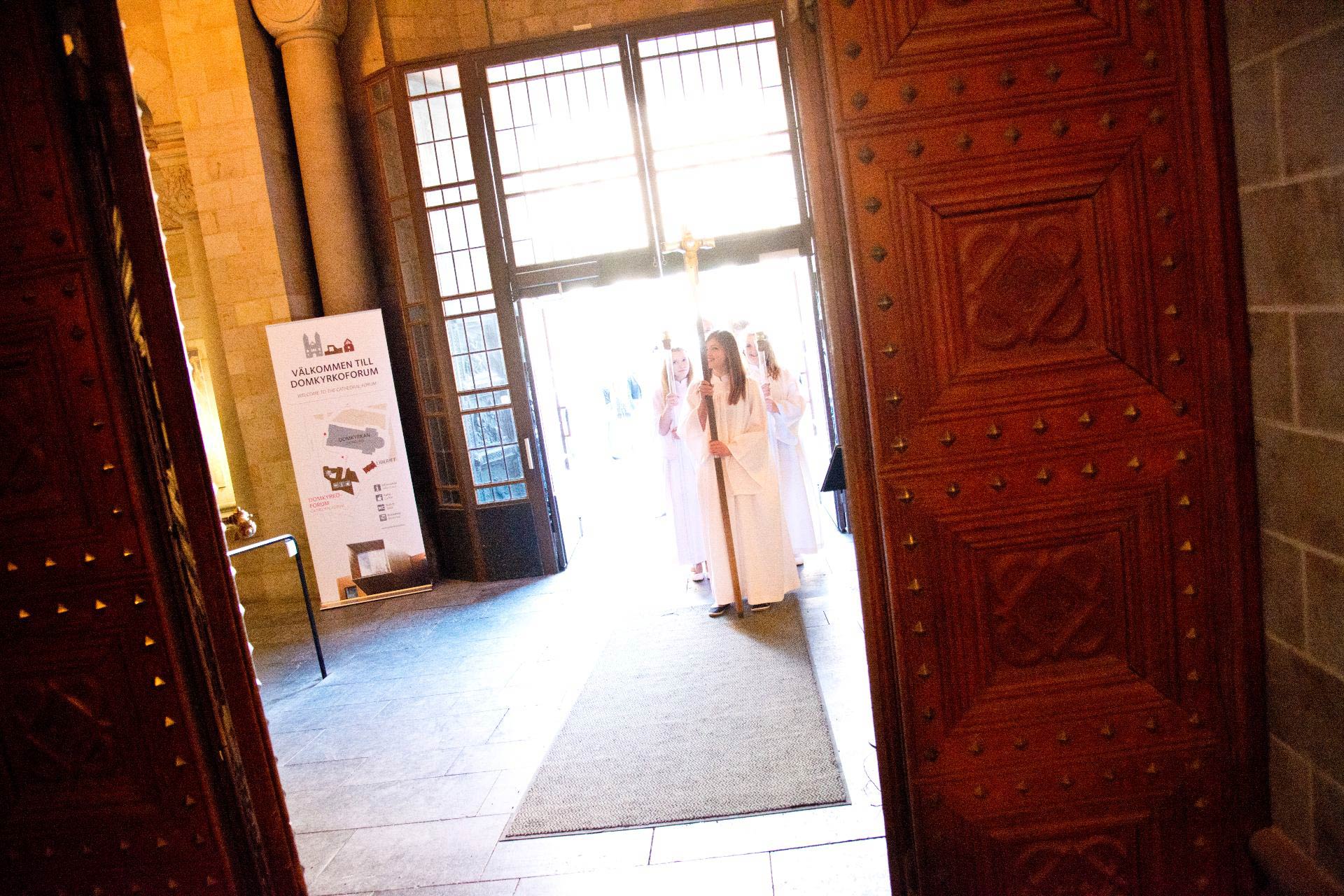 Konfirmander i vita kåpor på väg in i vapenhuset.