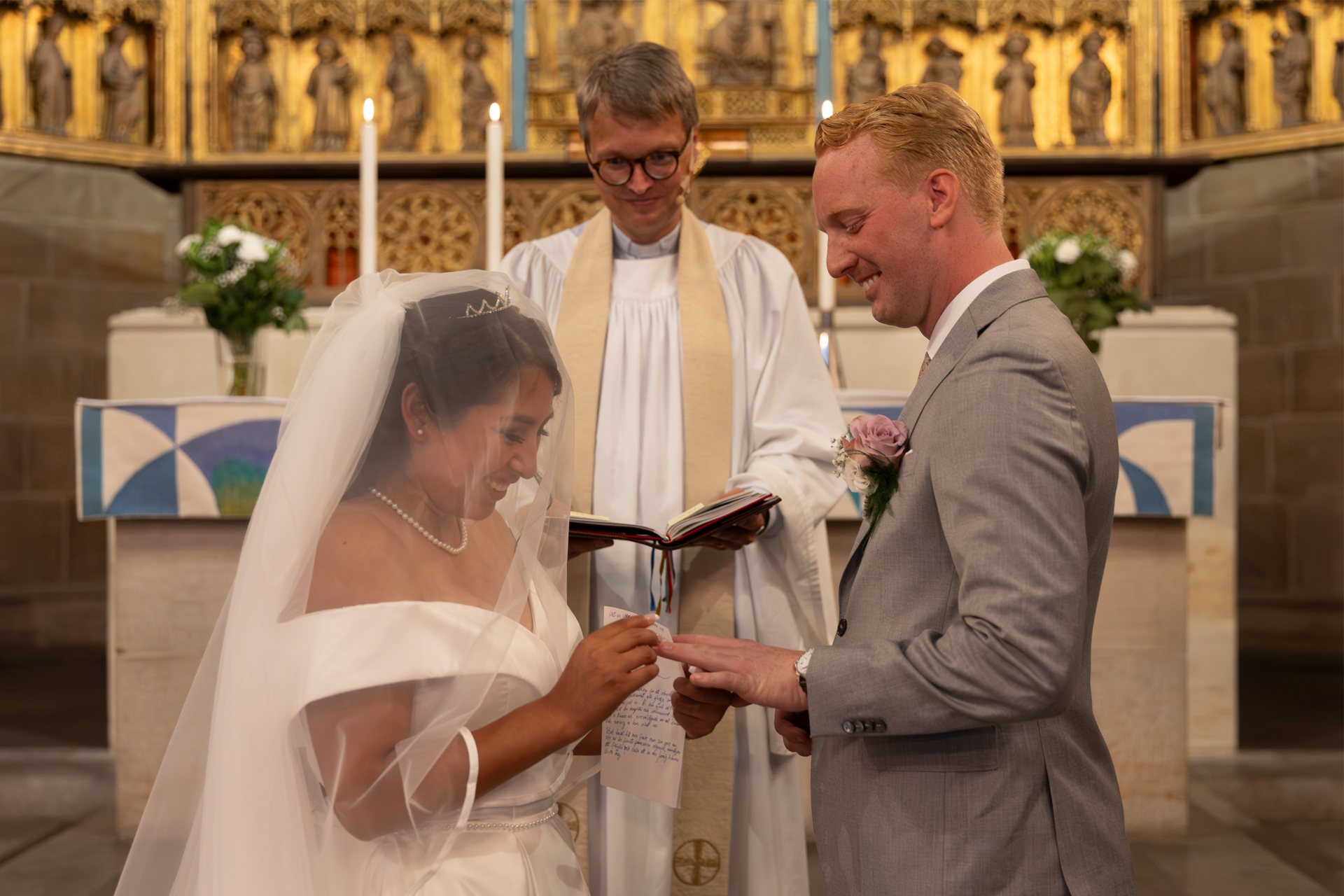 En präst viger ett par som just är i färd med att ta på ringarna. 