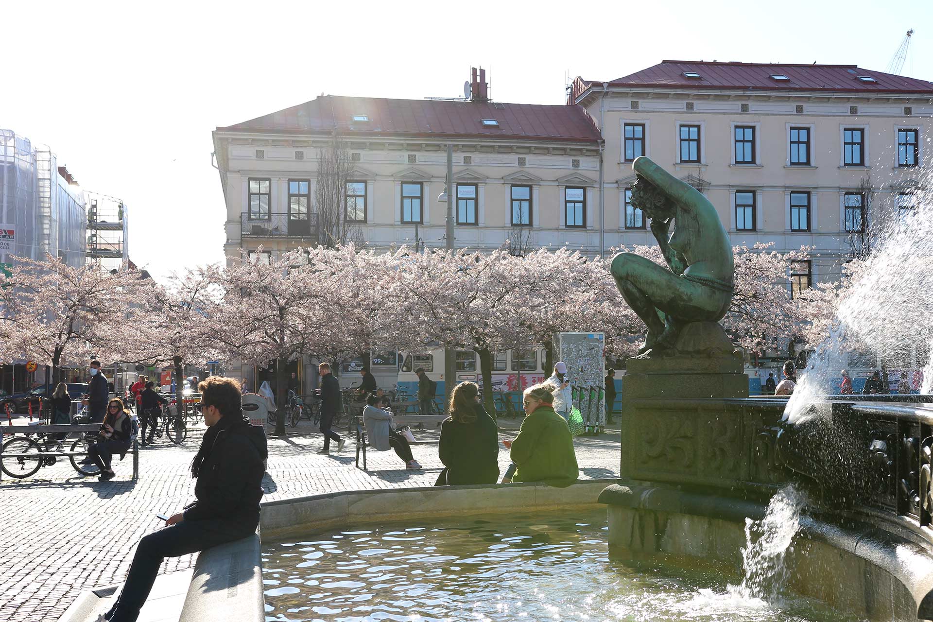 Några personer sitter på kanten på Järntorgets fontän.