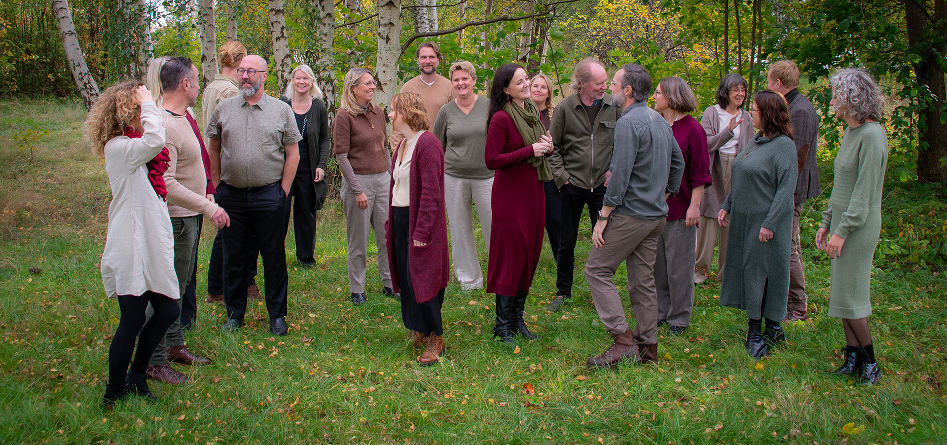 En grupp på tjugotalet personer står utspridda på en gräsmatta. De är inte uppställda för fotografering utan ser snarare ut att småprata med varandra.