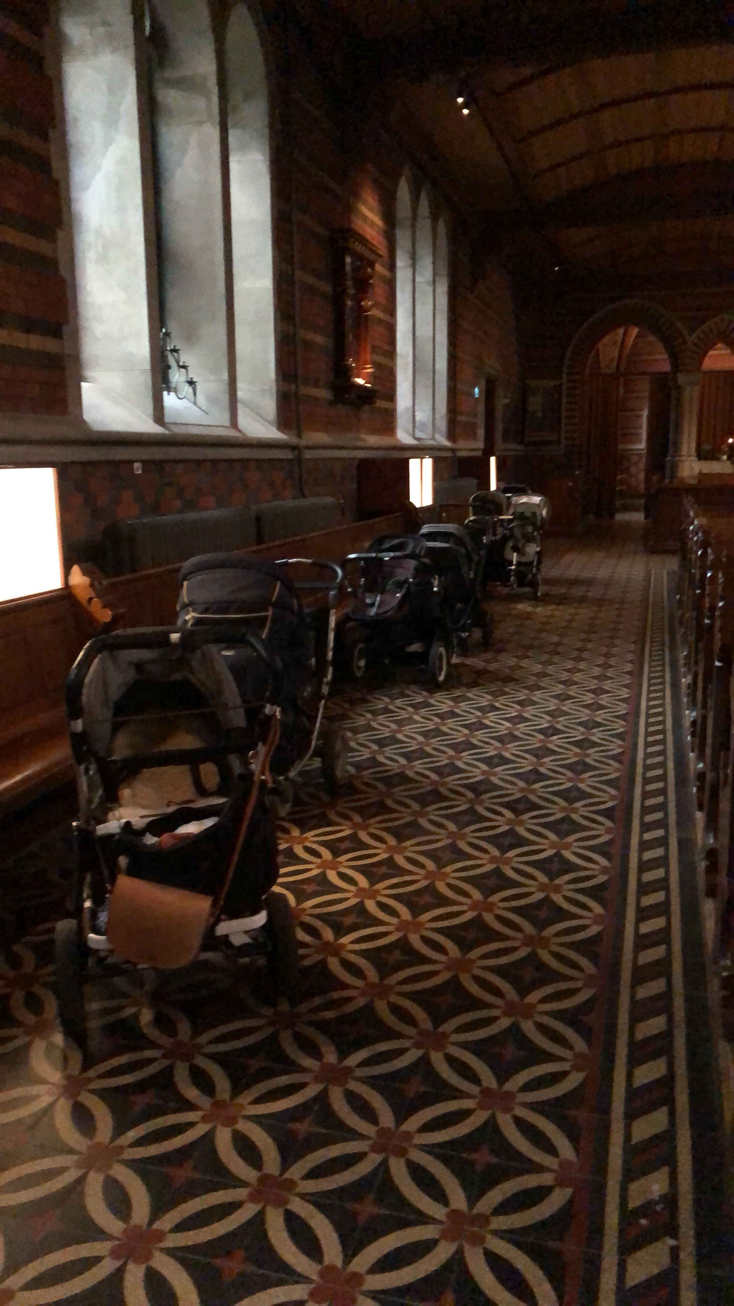 Man ser 6 barnvagnar som står på rad i en sidogång i Allhelgonakyrkan. Barnvagnarna är tomma för barn  och föräldrar är med på Babysång.