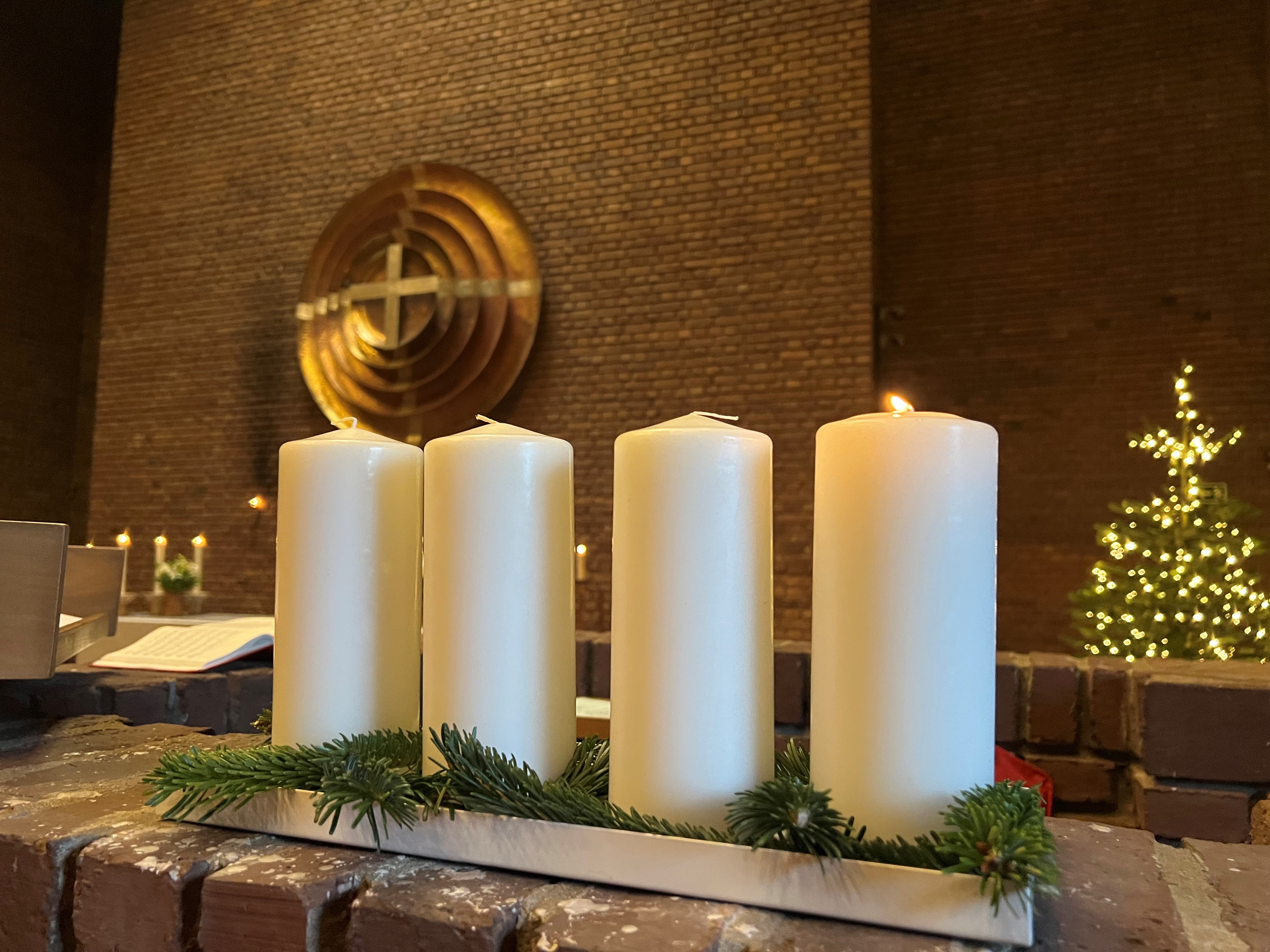 adventsljusstake i kyrkan med altarutsmyckning och julgran i bakgrunden