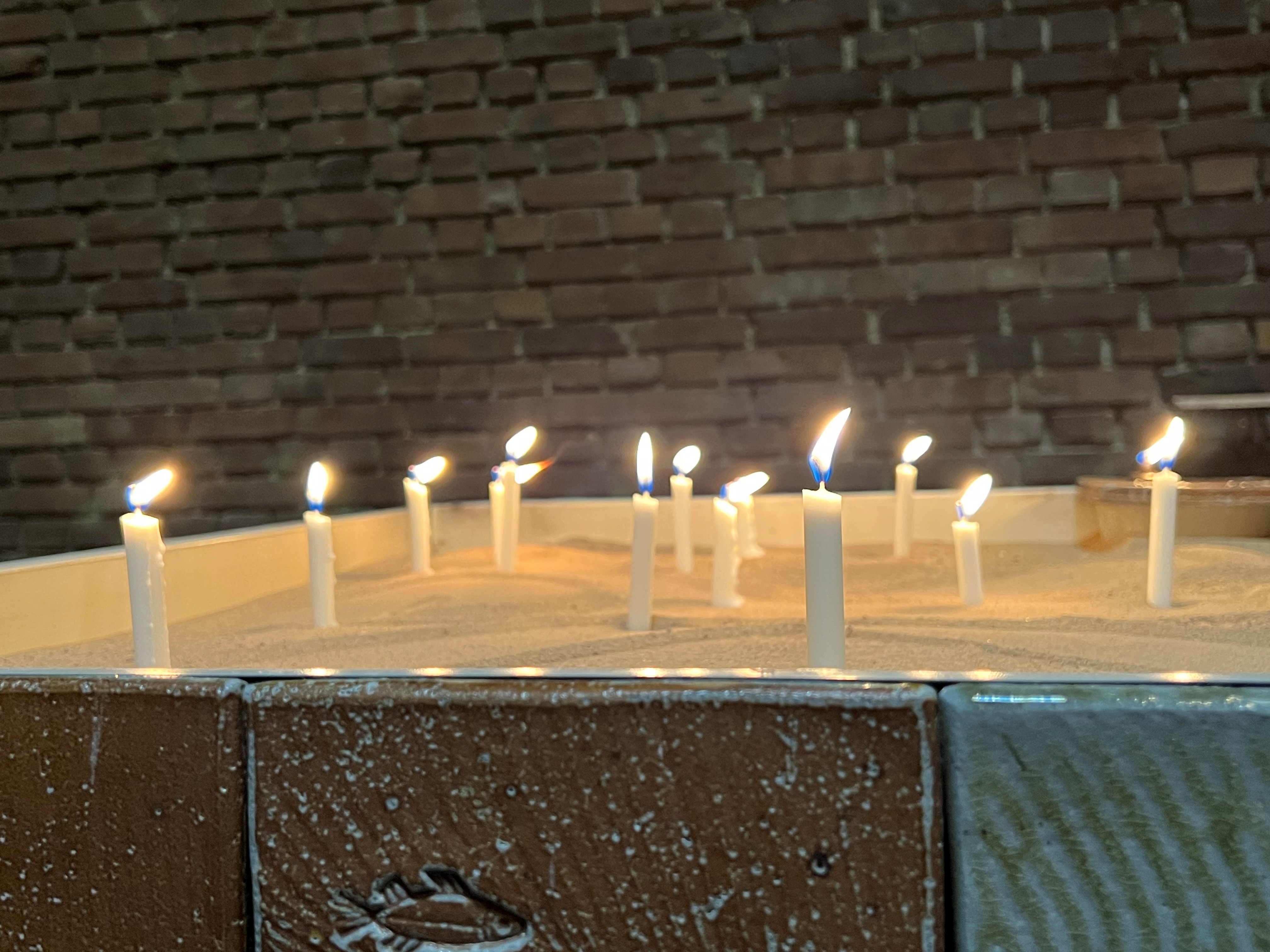 flera brinnande ljus i ljusbärare med sandbotten