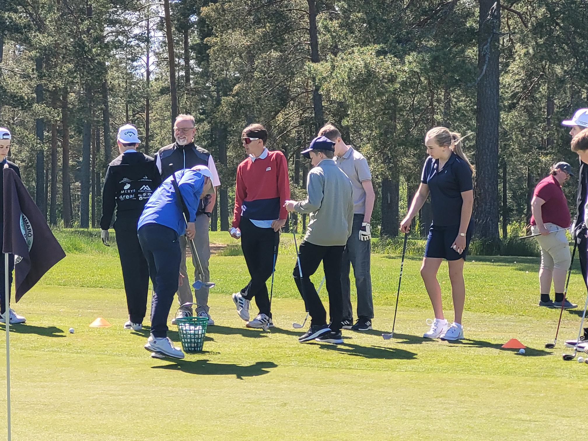 Sex konfaungdomar och en ledare spelar golf i solskenet en varm sommardag.