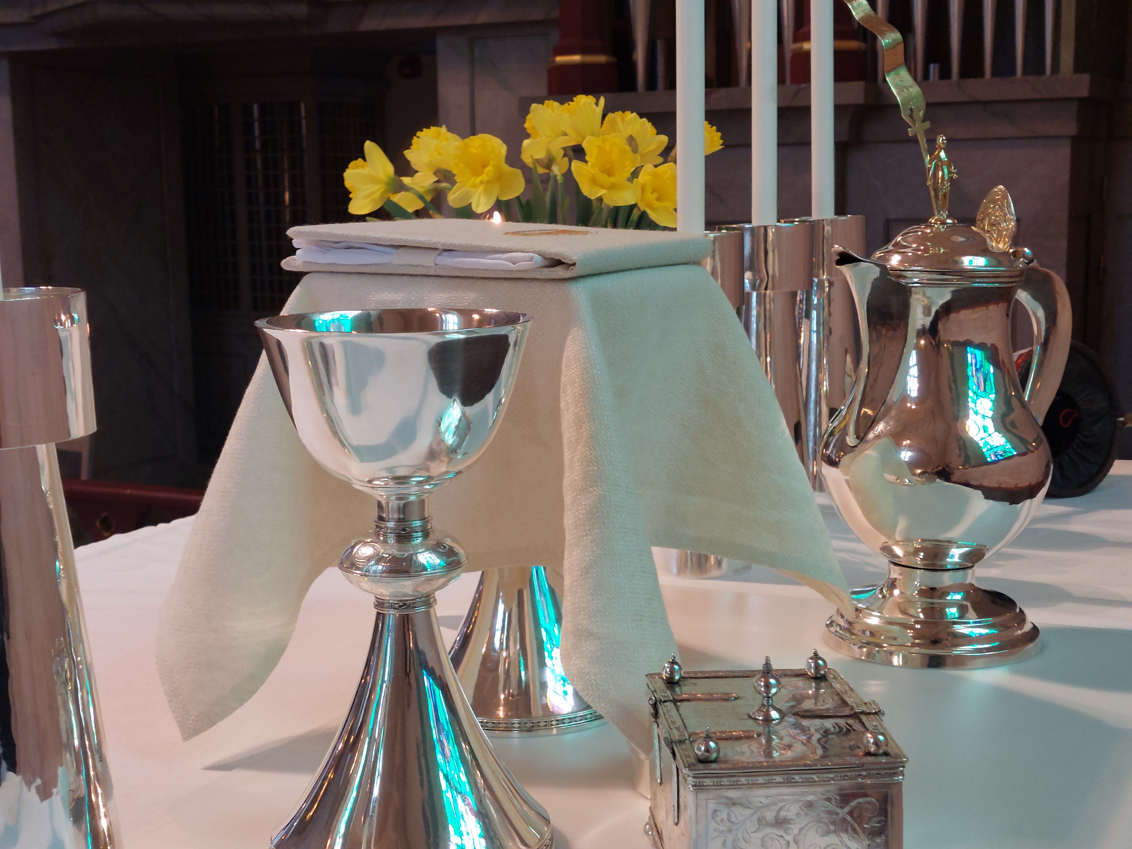 Altaret i Backens kyrka i påsktid. Påskliiljor. Nattvardsservisen med textilier i den vita liturgiska färgen. 