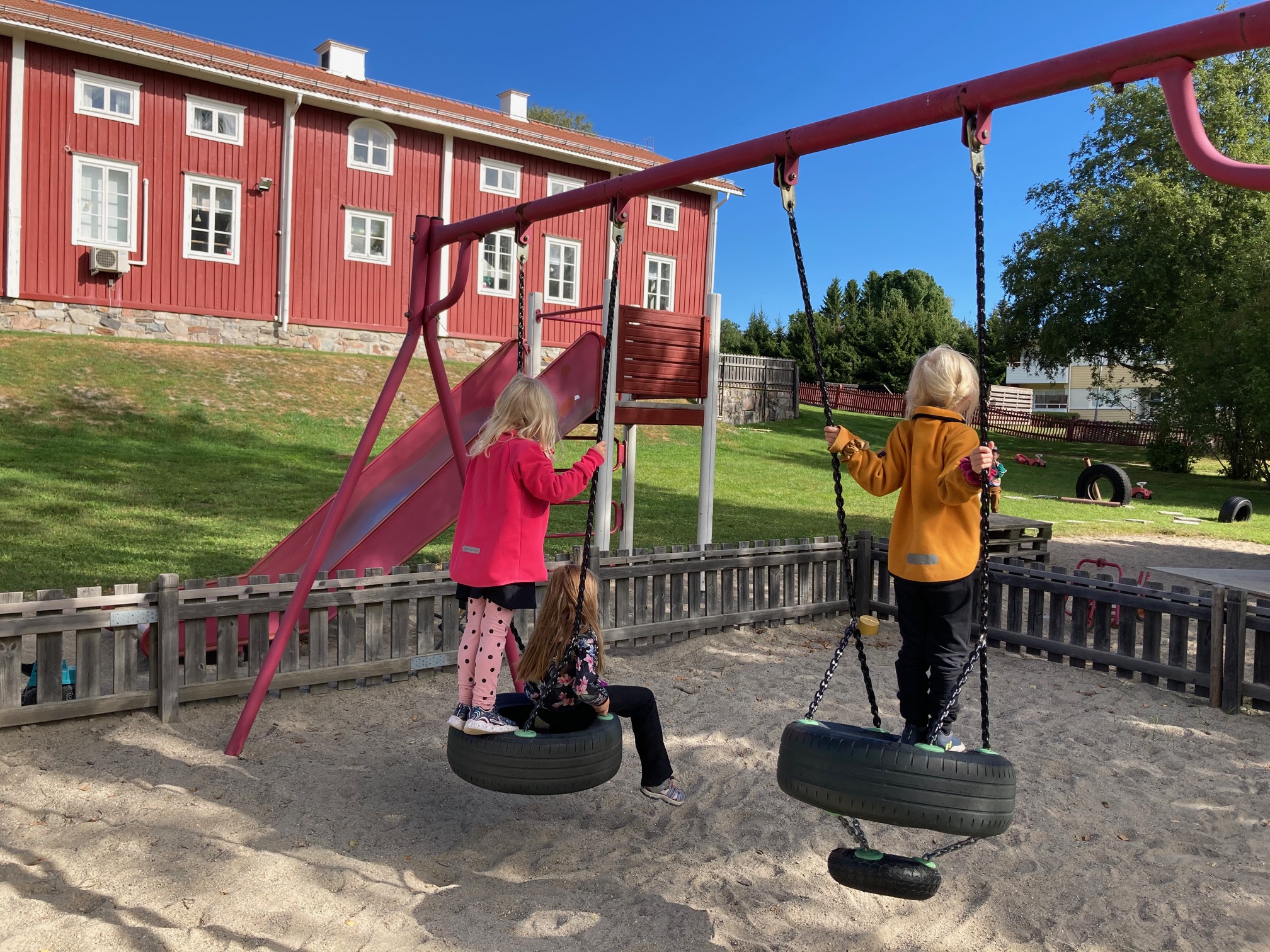 Förskolebarn gungar utomhus