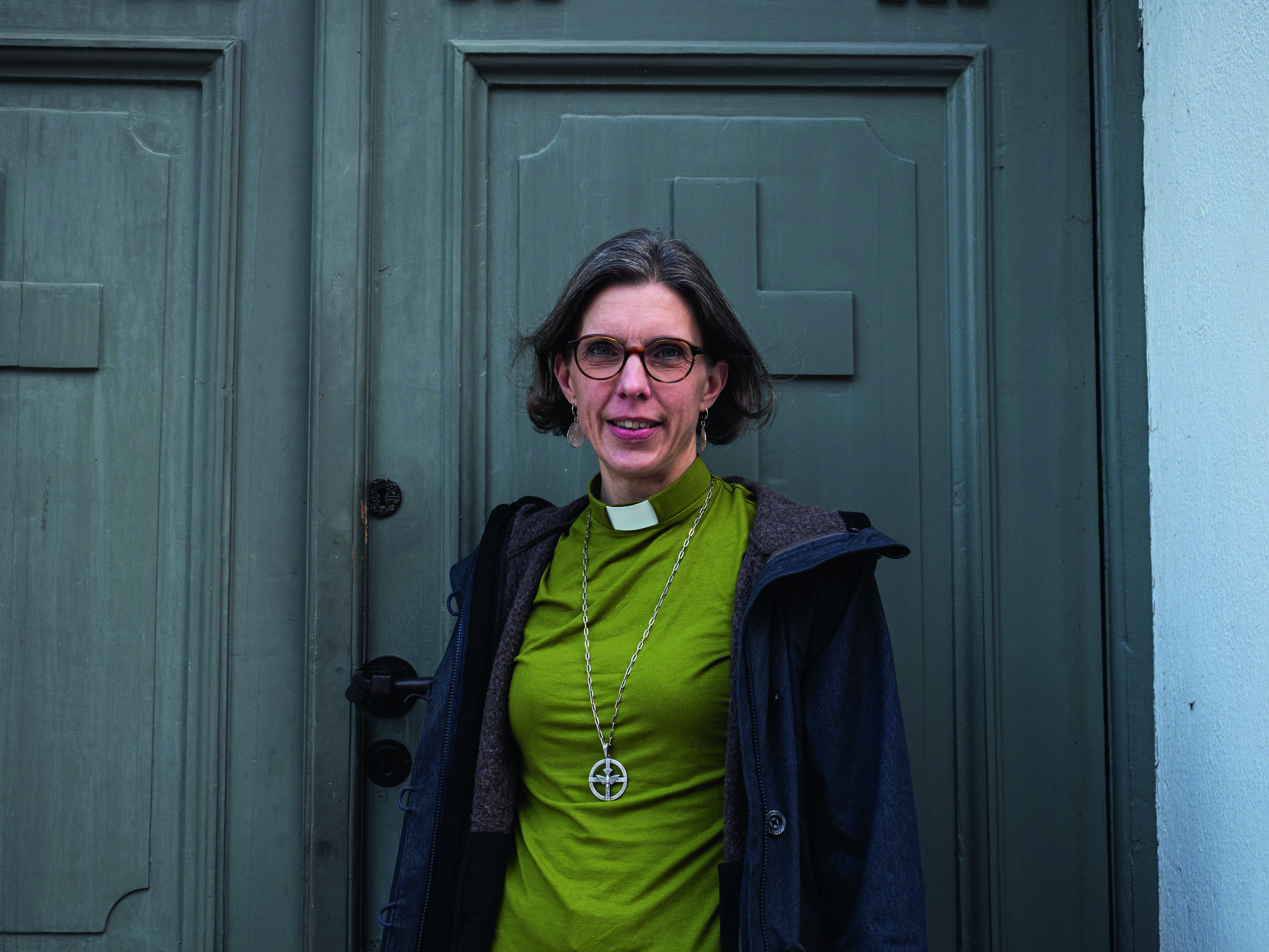 Diakon Kristina står vid kyrkporten.