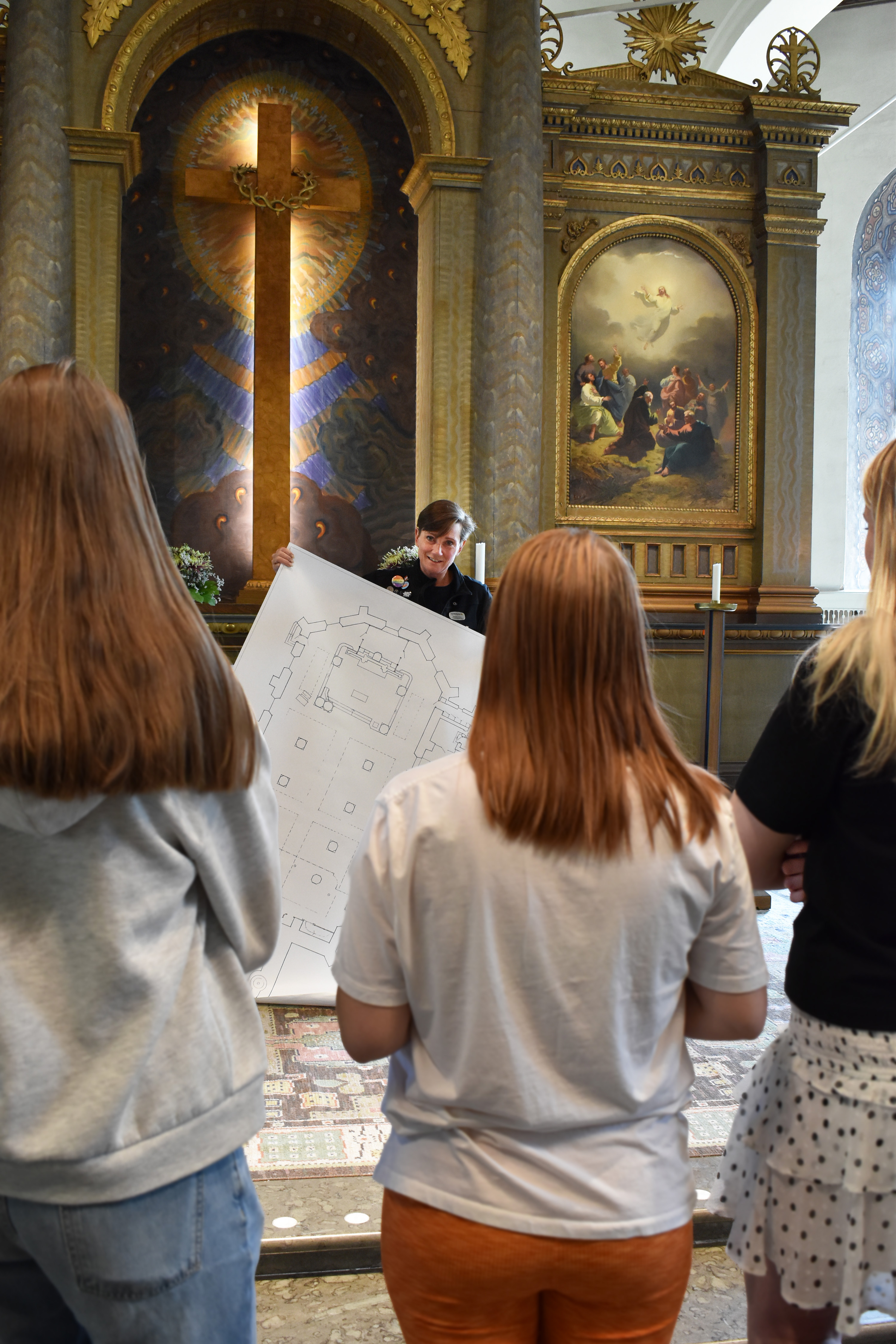 Kvinna visar ritning på kyrka för ungdomar inne i kyrkan.