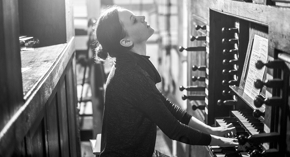 Kvinna spelar på stor orgel.