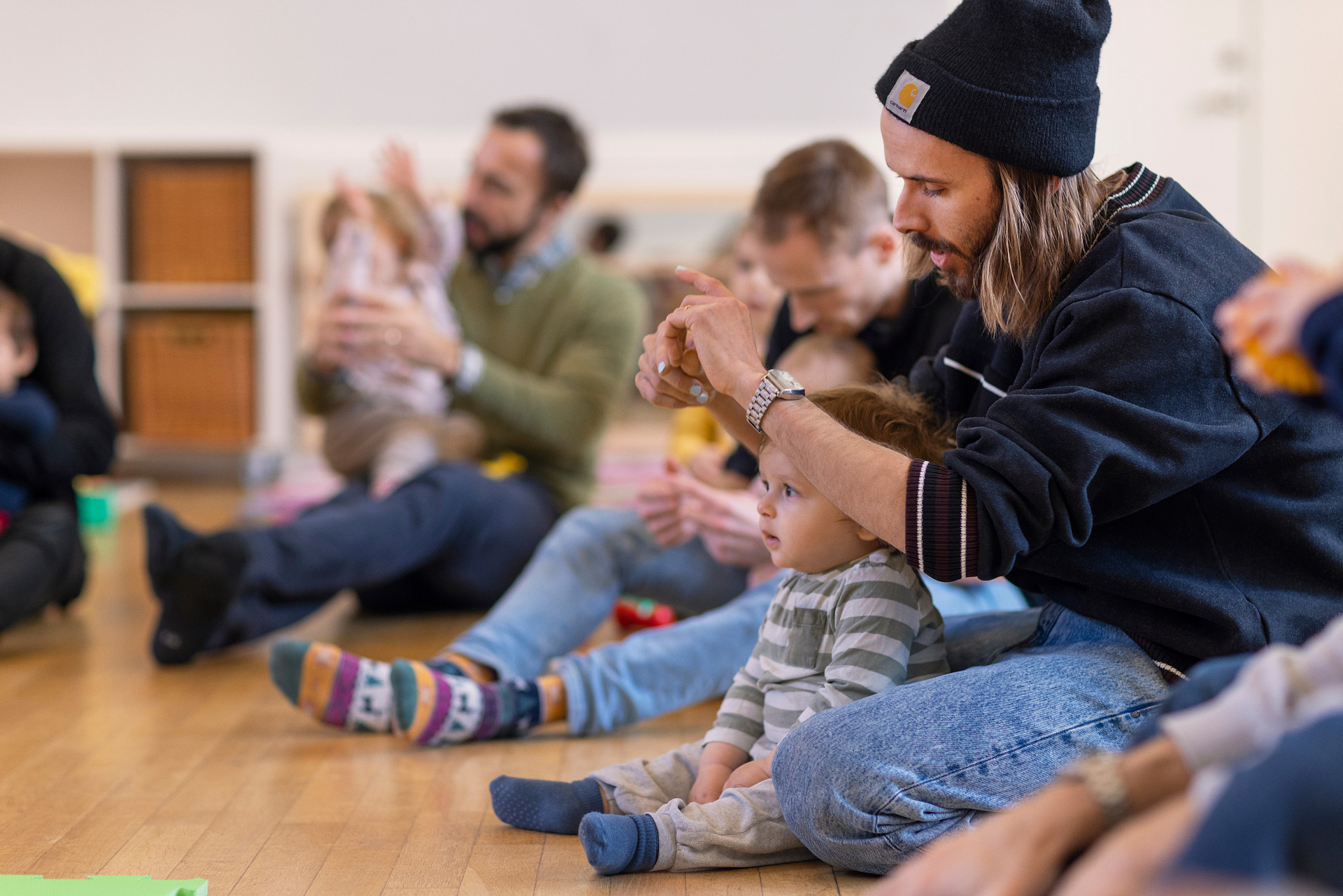 Några pappor sitter på golvet och leker med sina barn