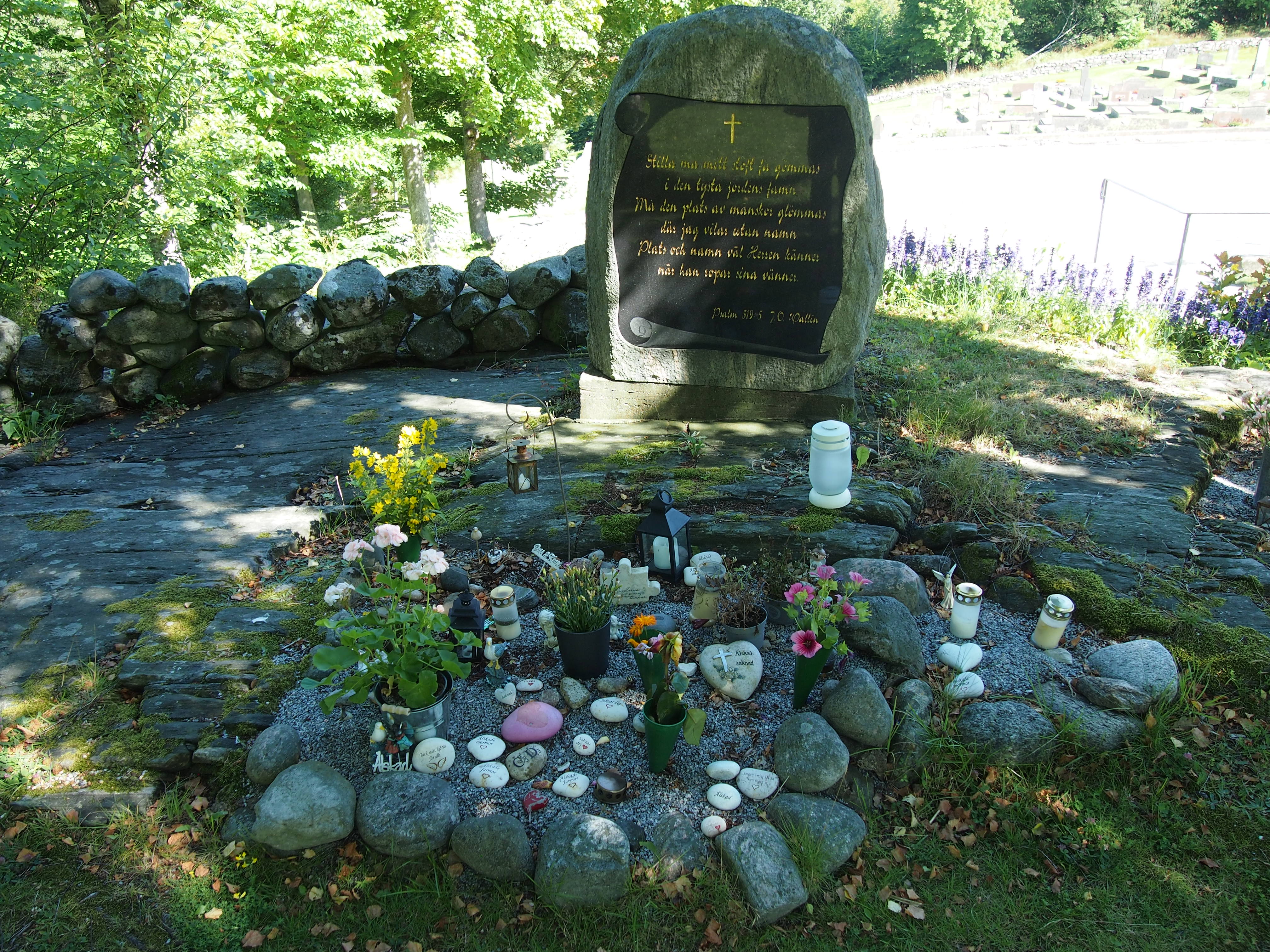 Minneslunden på Stenkyrka kyrkogård med ljus, blommor och minnessaker