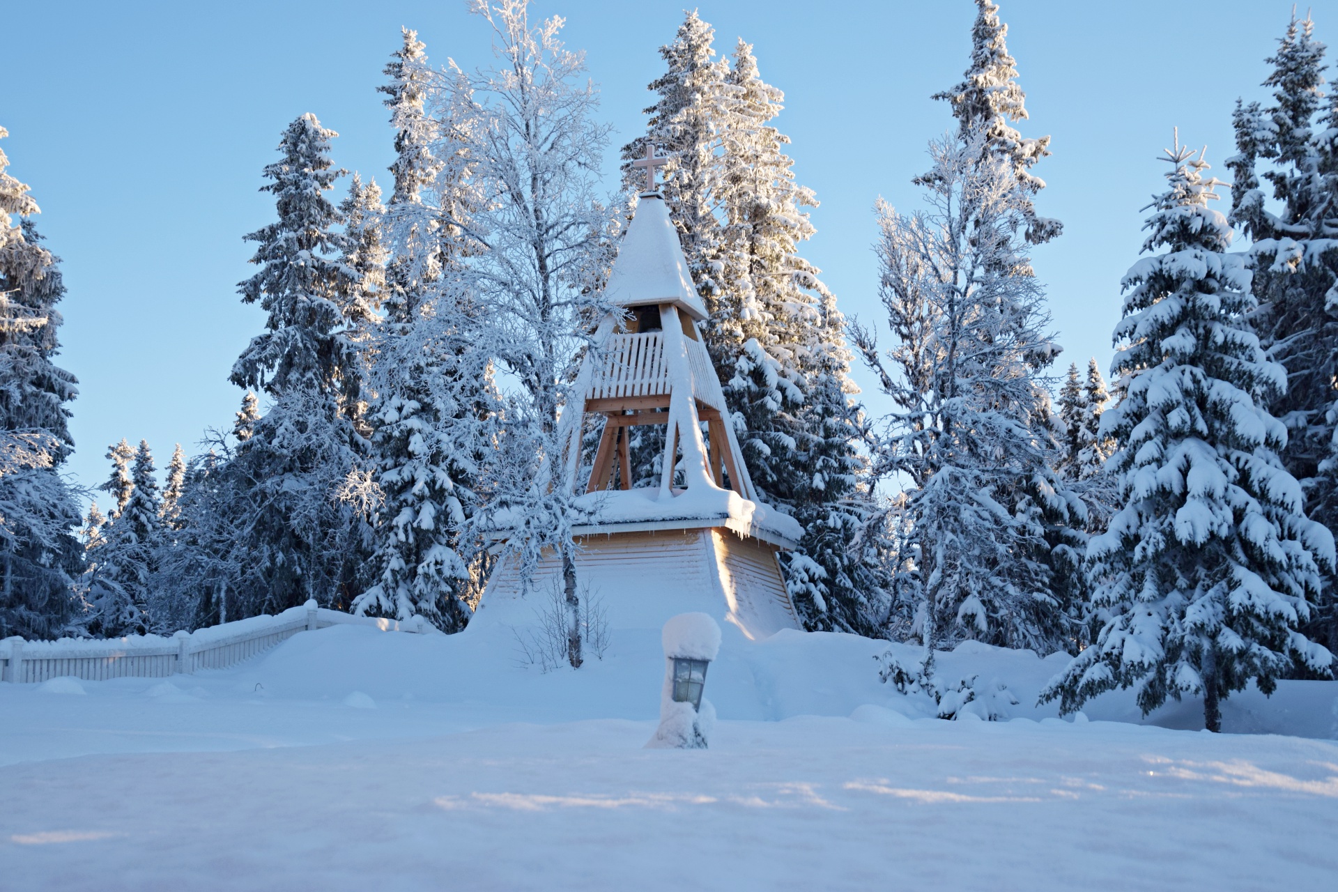 En fin vinterdag. Snön ligger tung på granarna och på klockstapeln.