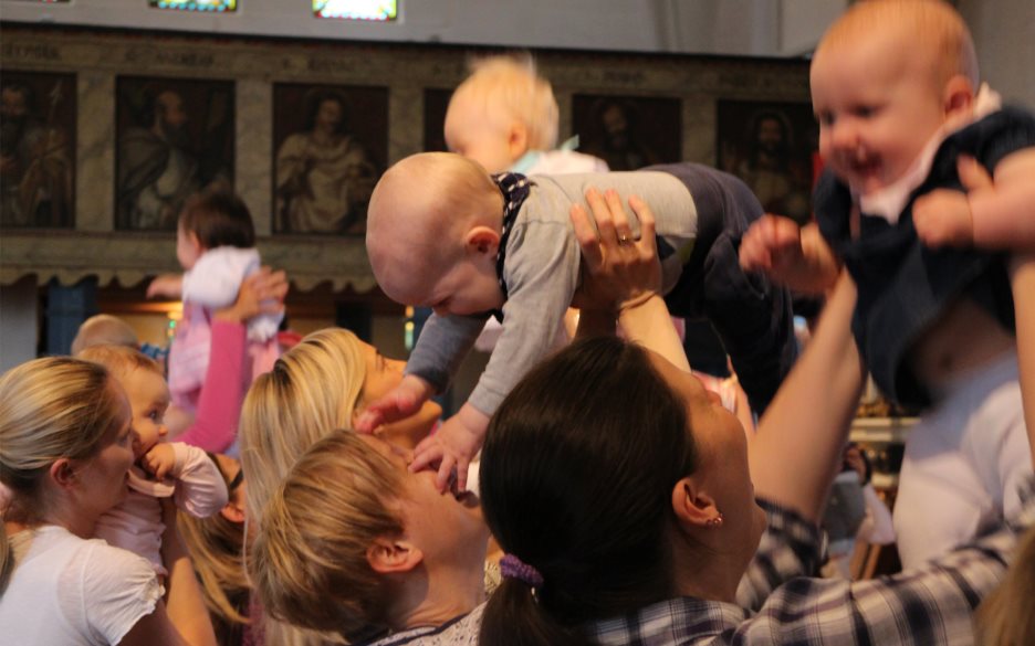 Glada bebisar/barn lyfts upp i luften i kyrka
