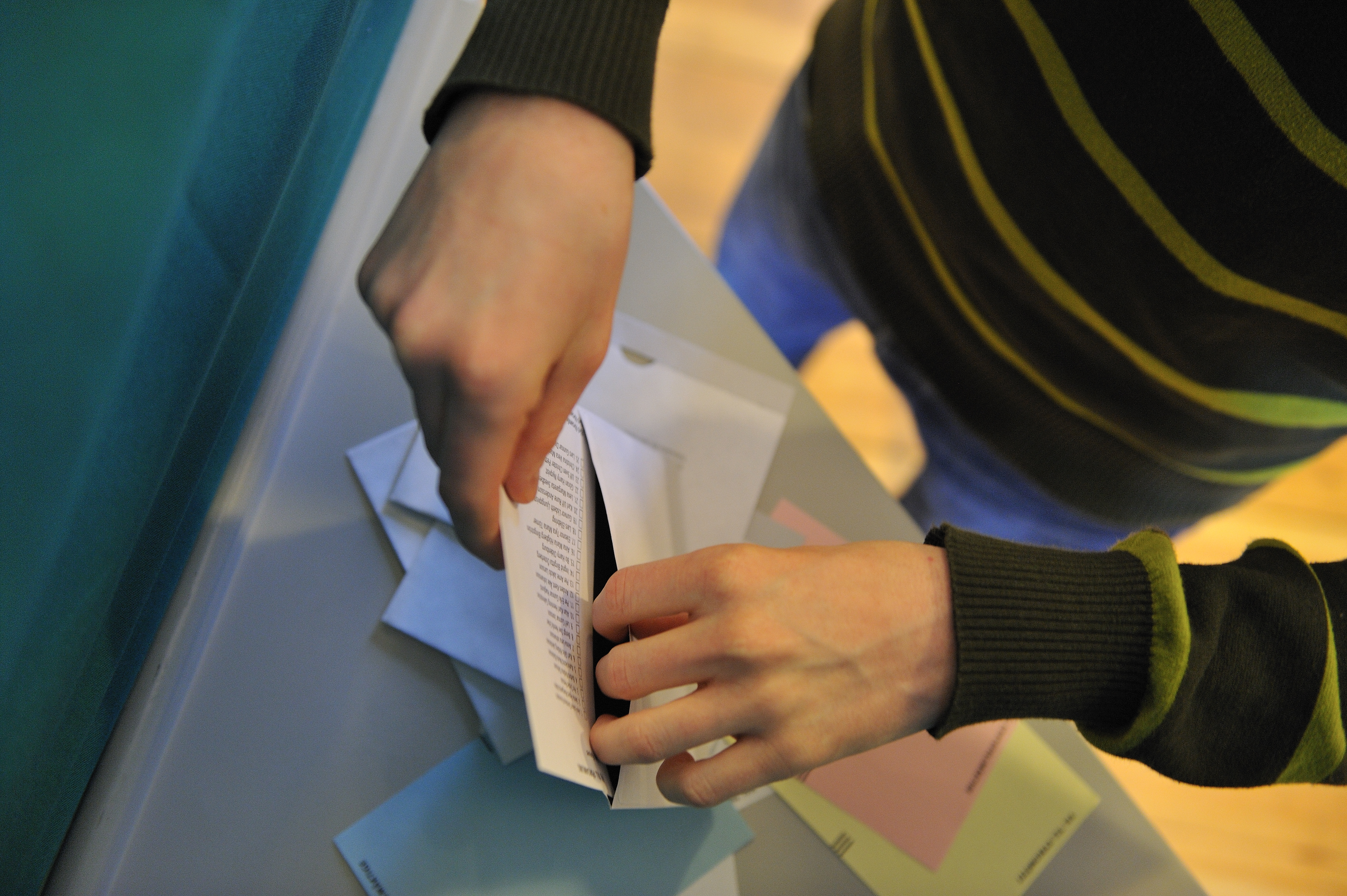 En person stoppar ner en valsedel i ett kuvert.